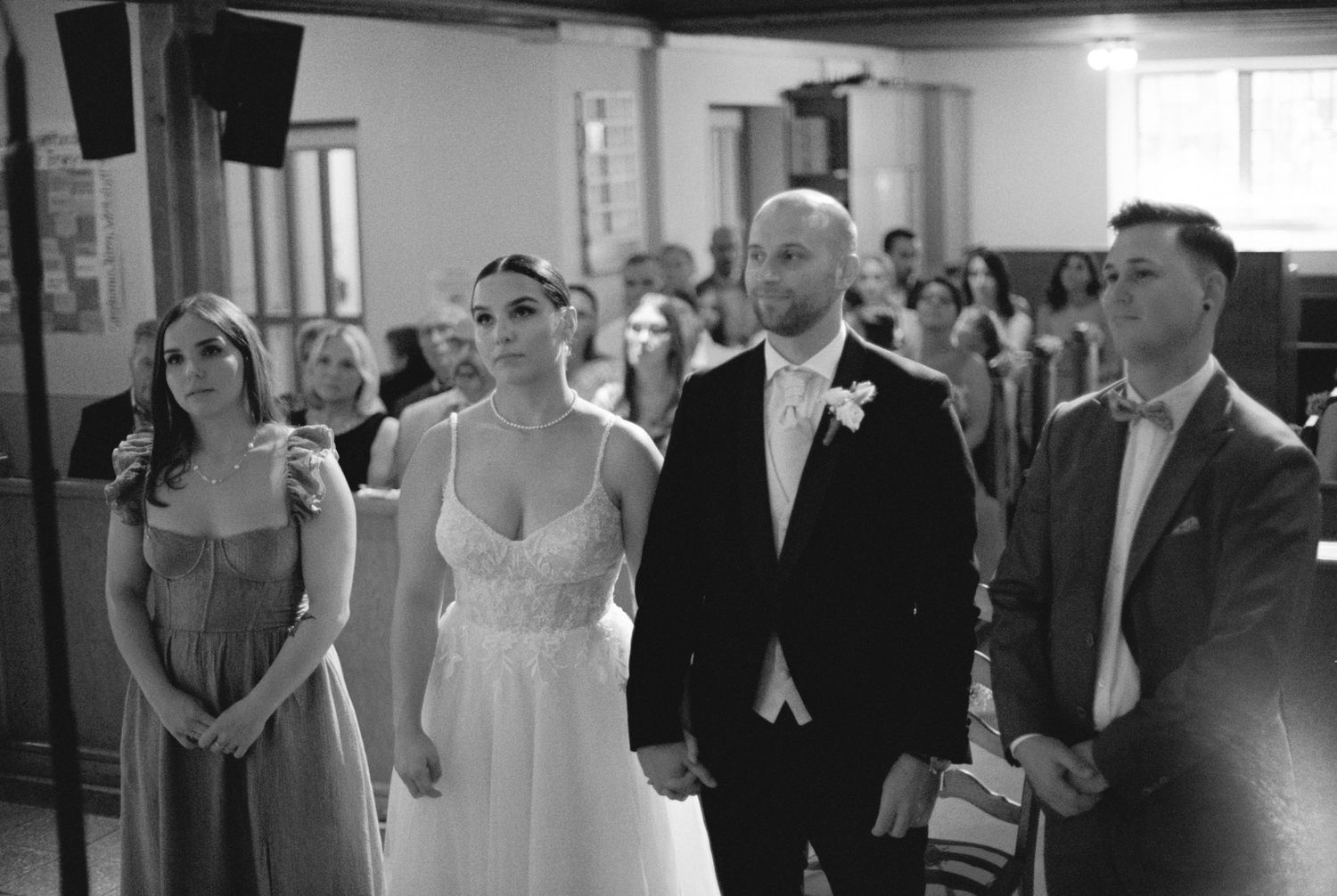 Wedding party members standing in a church during a ceremony.