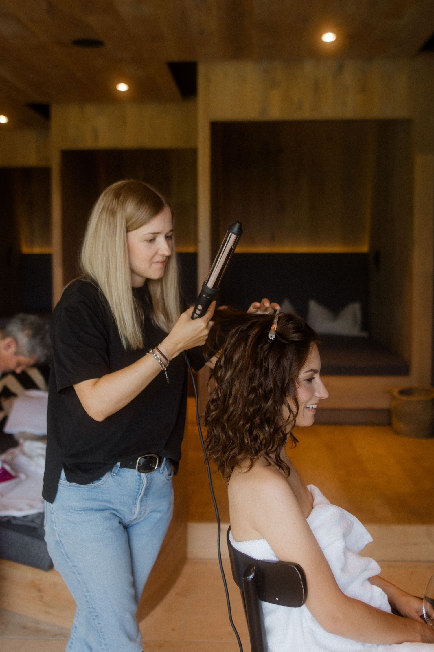 Hairstylist styling bride's hair in a modern indoor setting.