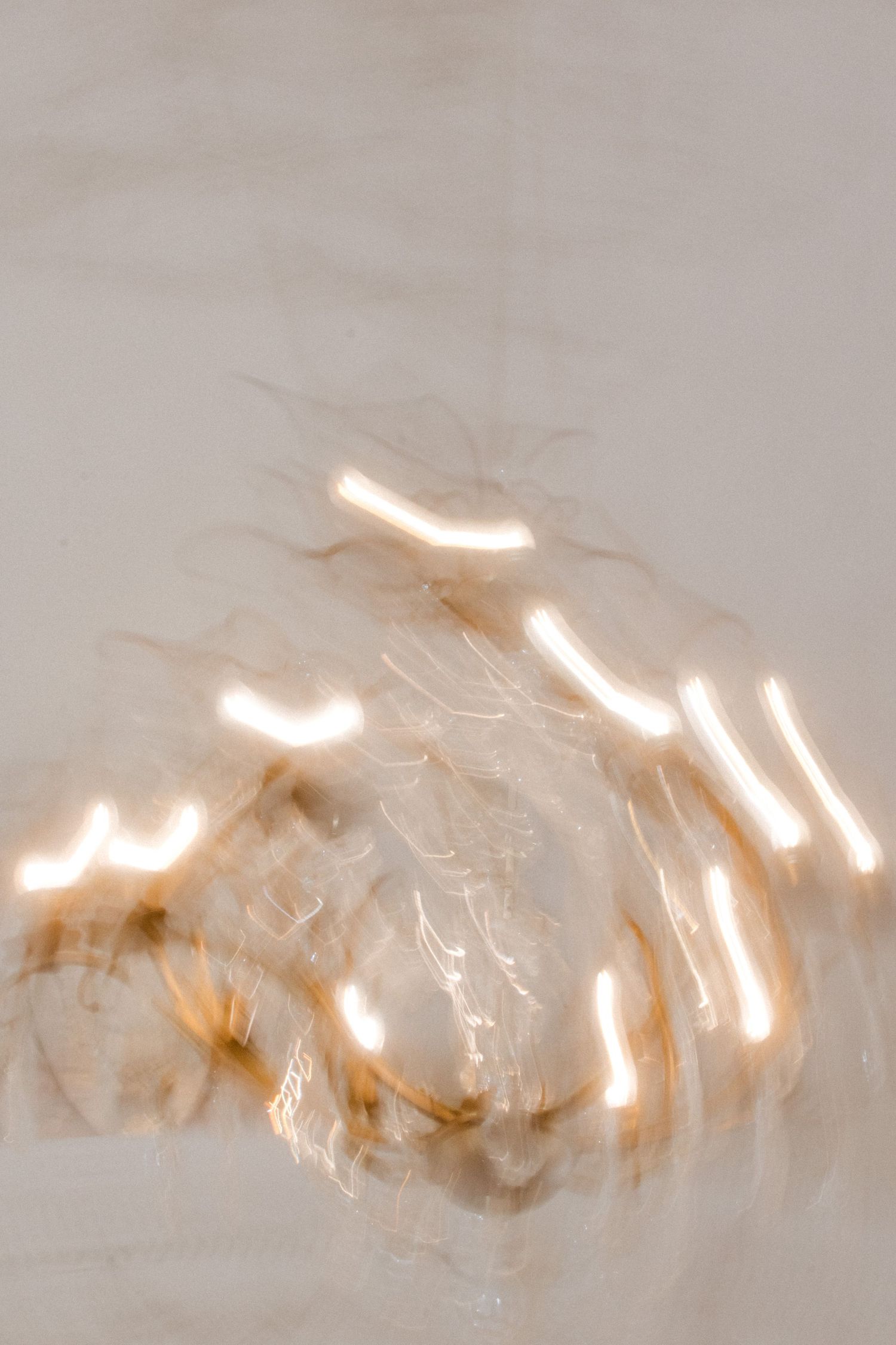 Abstract light patterns creating a soft, ethereal glow against a pale background.