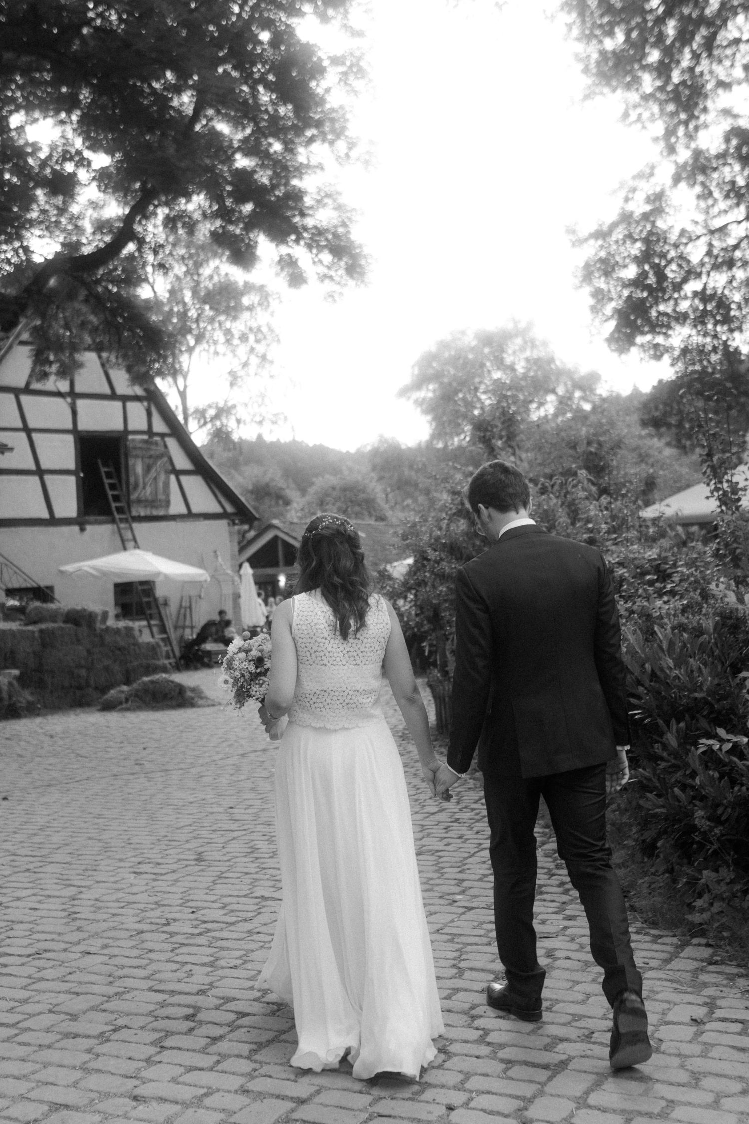A romantic couple poses against a stone wall overlooking a scenic landscape.