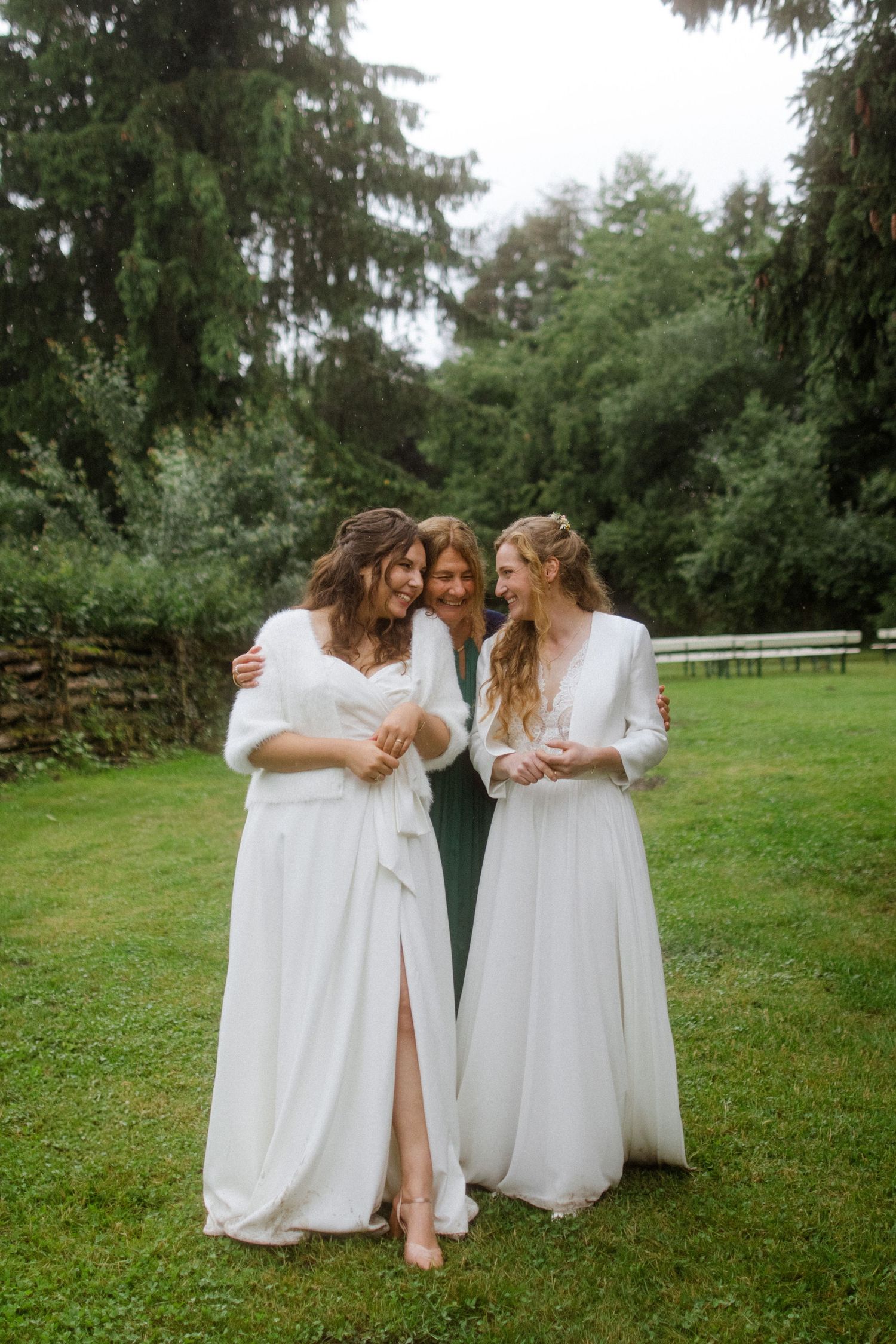 Group wearing matching white dresses walking together on grassy lawn.