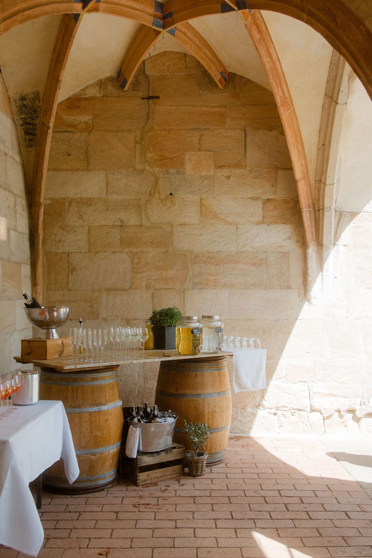 Wine barrels and glassware set up in a rustic stone archway for event service.