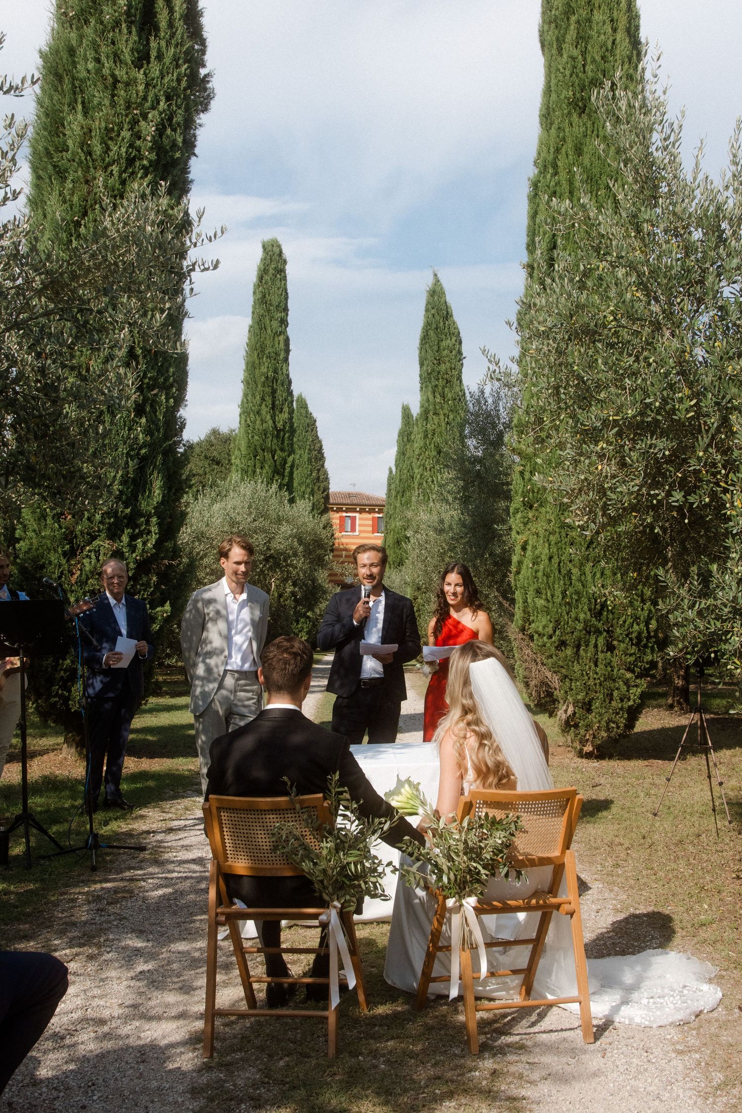 Wedding ceremony setup on a cypress-lined path in an Italian garden.