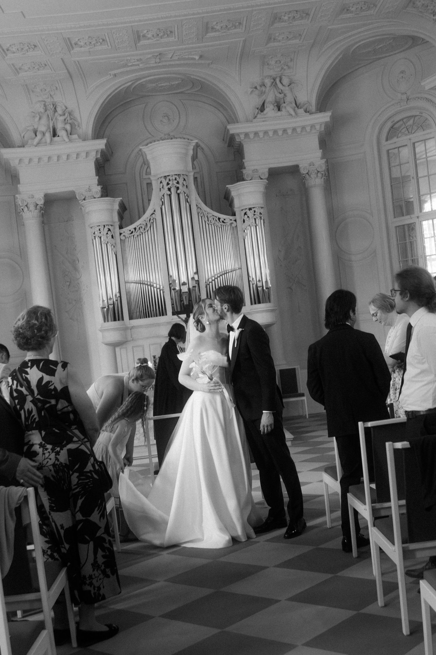 Wedding ceremony in a grand church with ornate organ pipes and classical architecture.