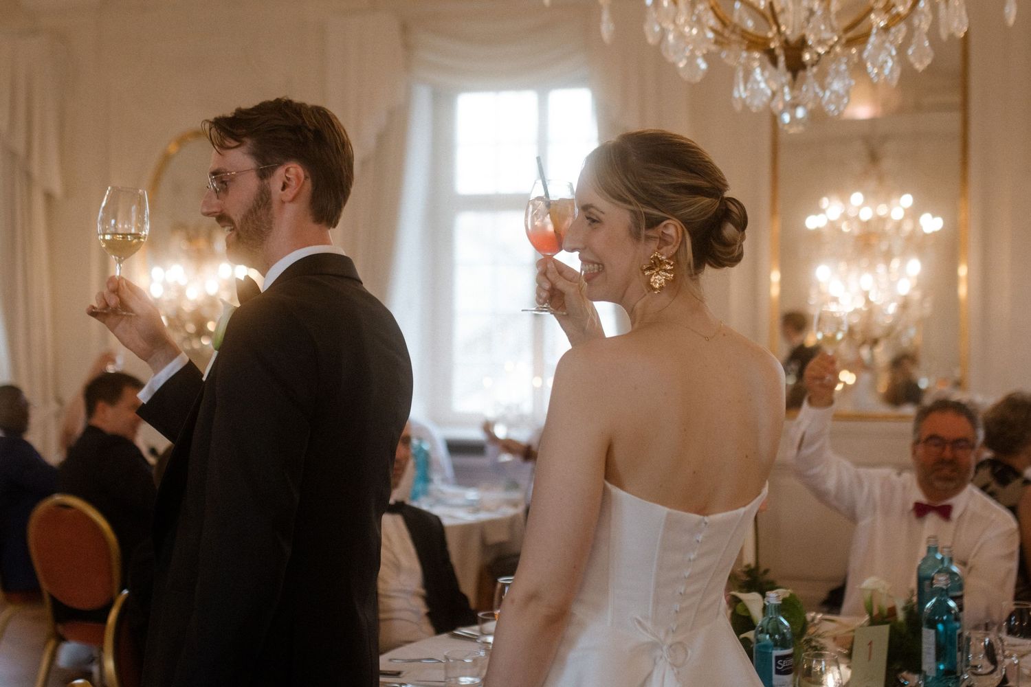 Elegant wedding reception with guests mingling beneath crystal chandeliers.