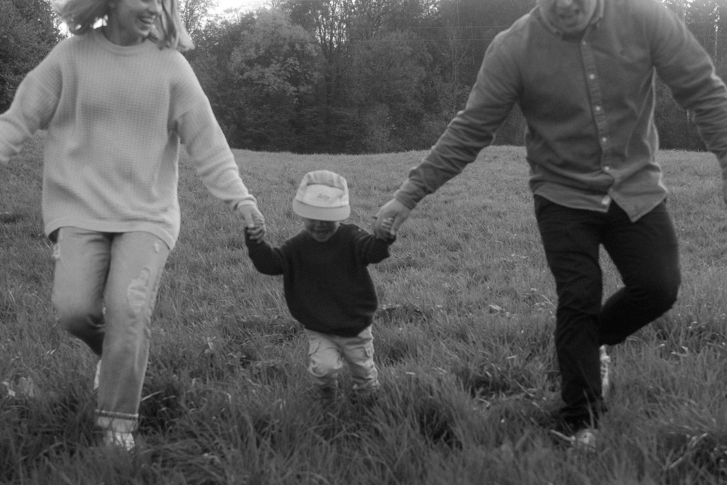 Black and white photo of people walking through a grassy field.