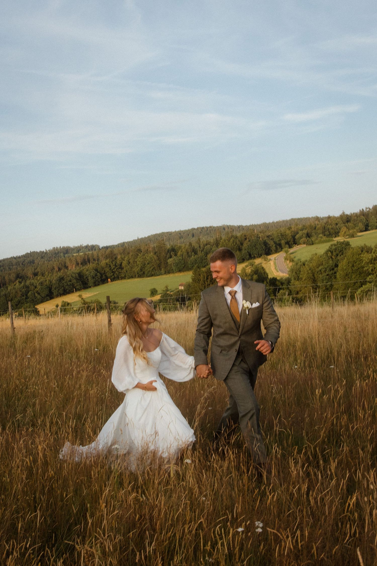 A couple dances and spins through a golden field at sunset.