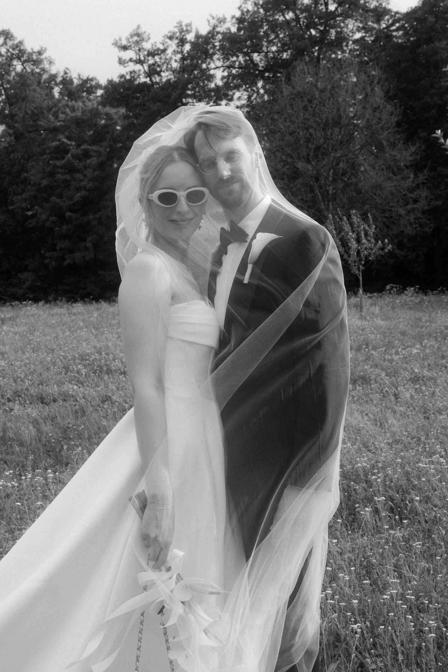Black and white wedding photos show a couple embracing in a sunlit field.