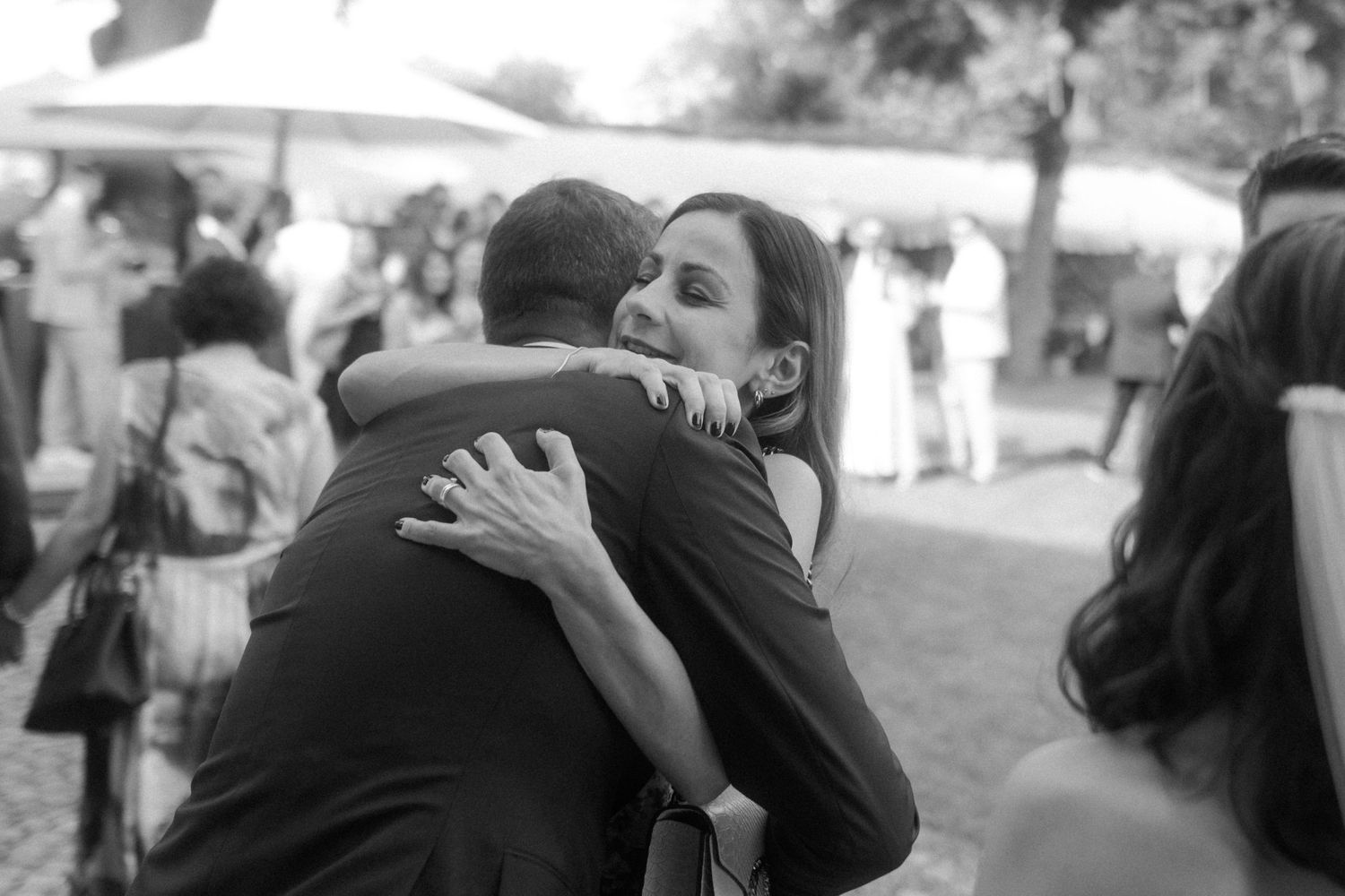Black and white capture of heartfelt hug during outdoor wedding celebration.