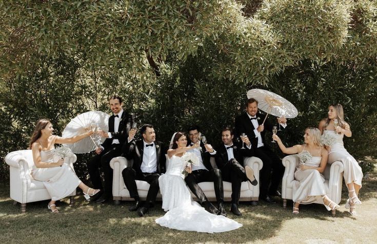 Fun and playful wedding party photo with formal attire in garden setting.