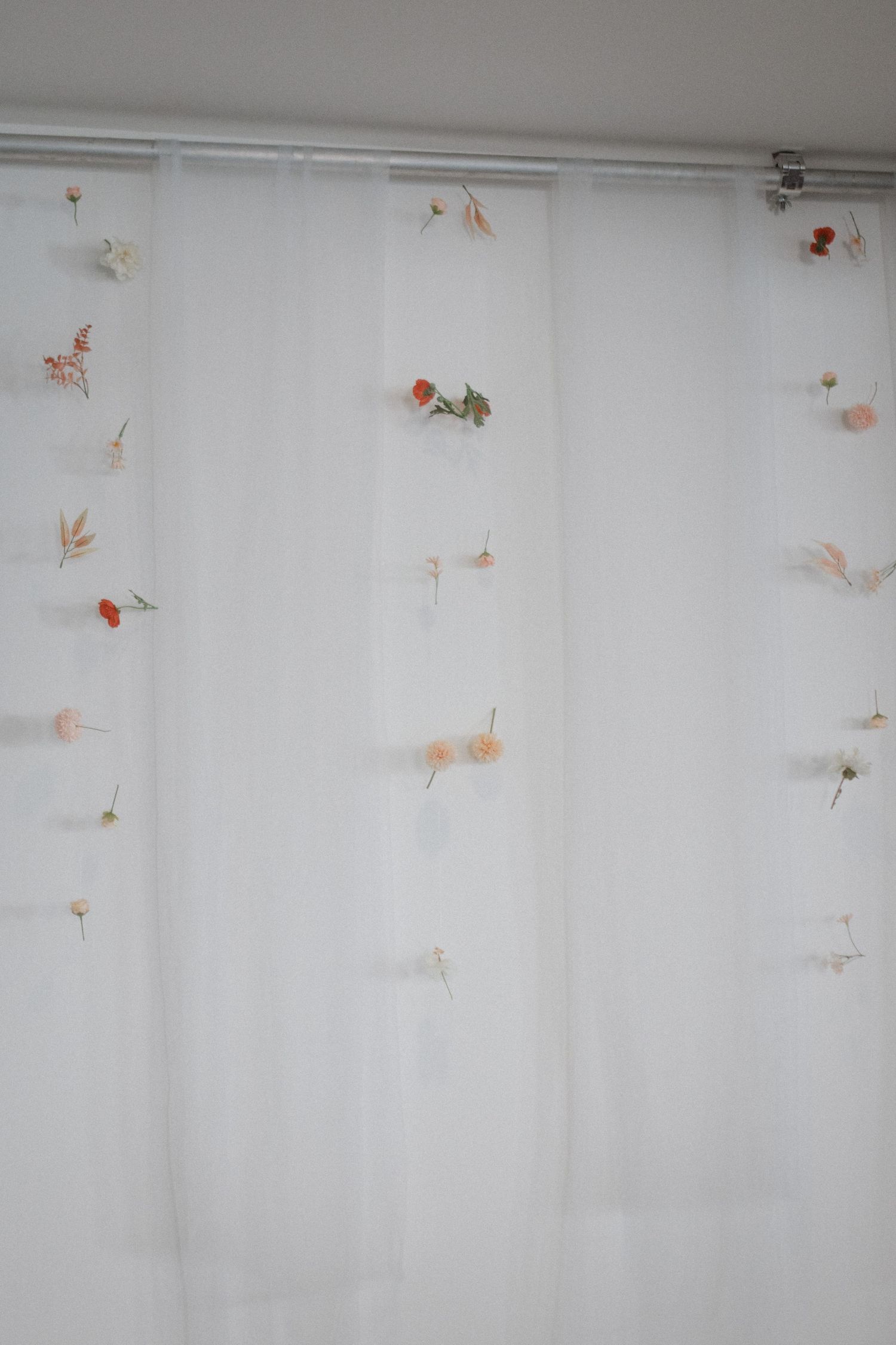 Sheer white curtain decorated with delicate dried flowers and botanicals.