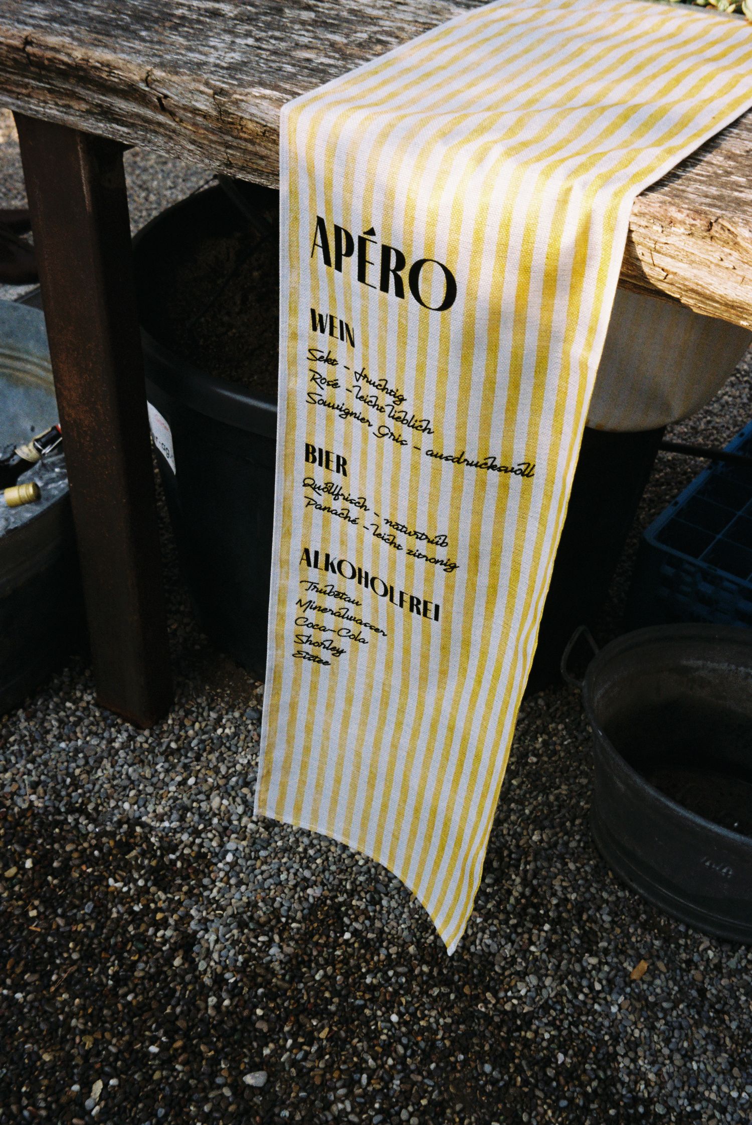 A vintage-style striped menu runner with 'APERO' text displayed on a rustic wooden surface.