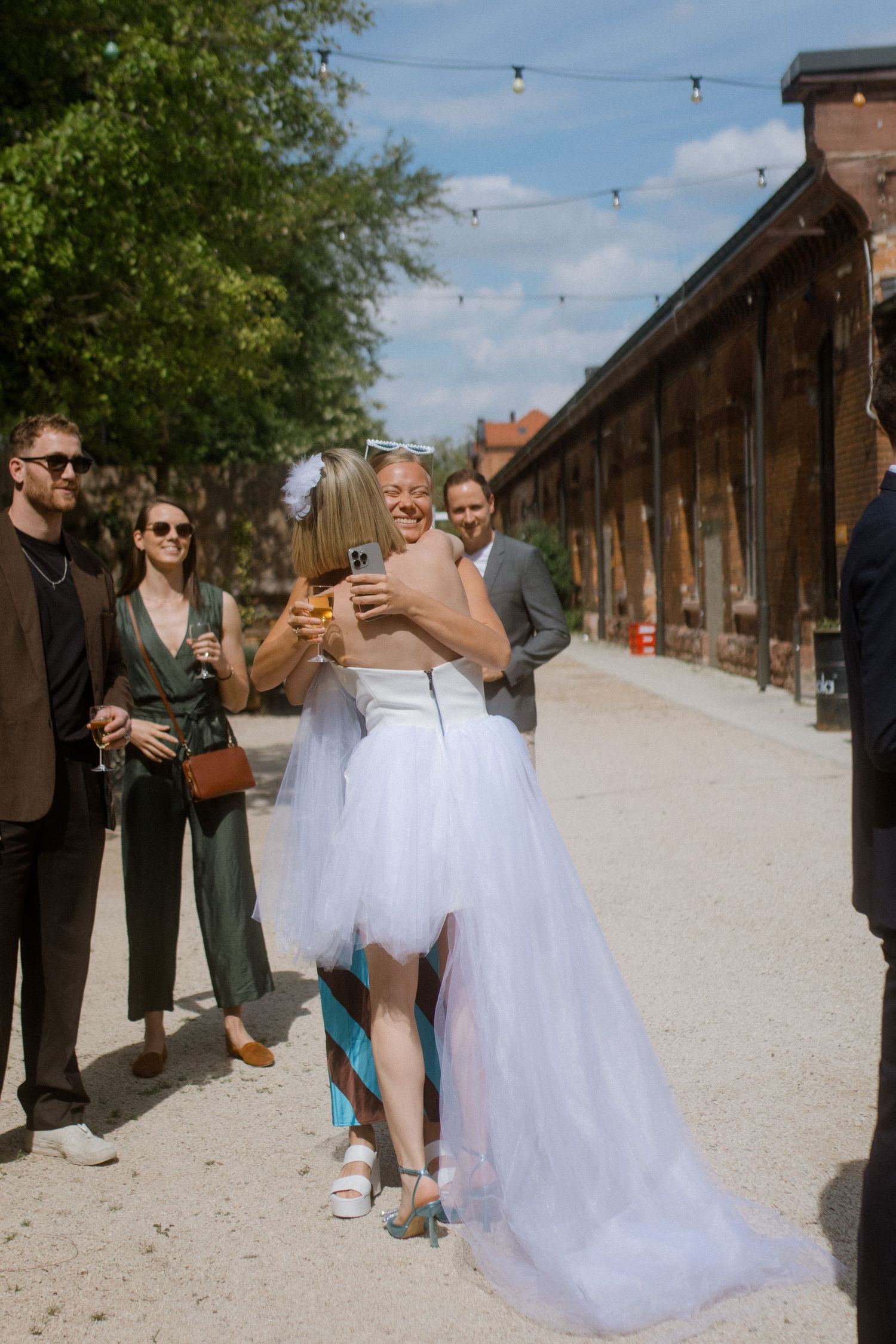 A wedding celebration outside a rustic building with guests watching a special moment.
