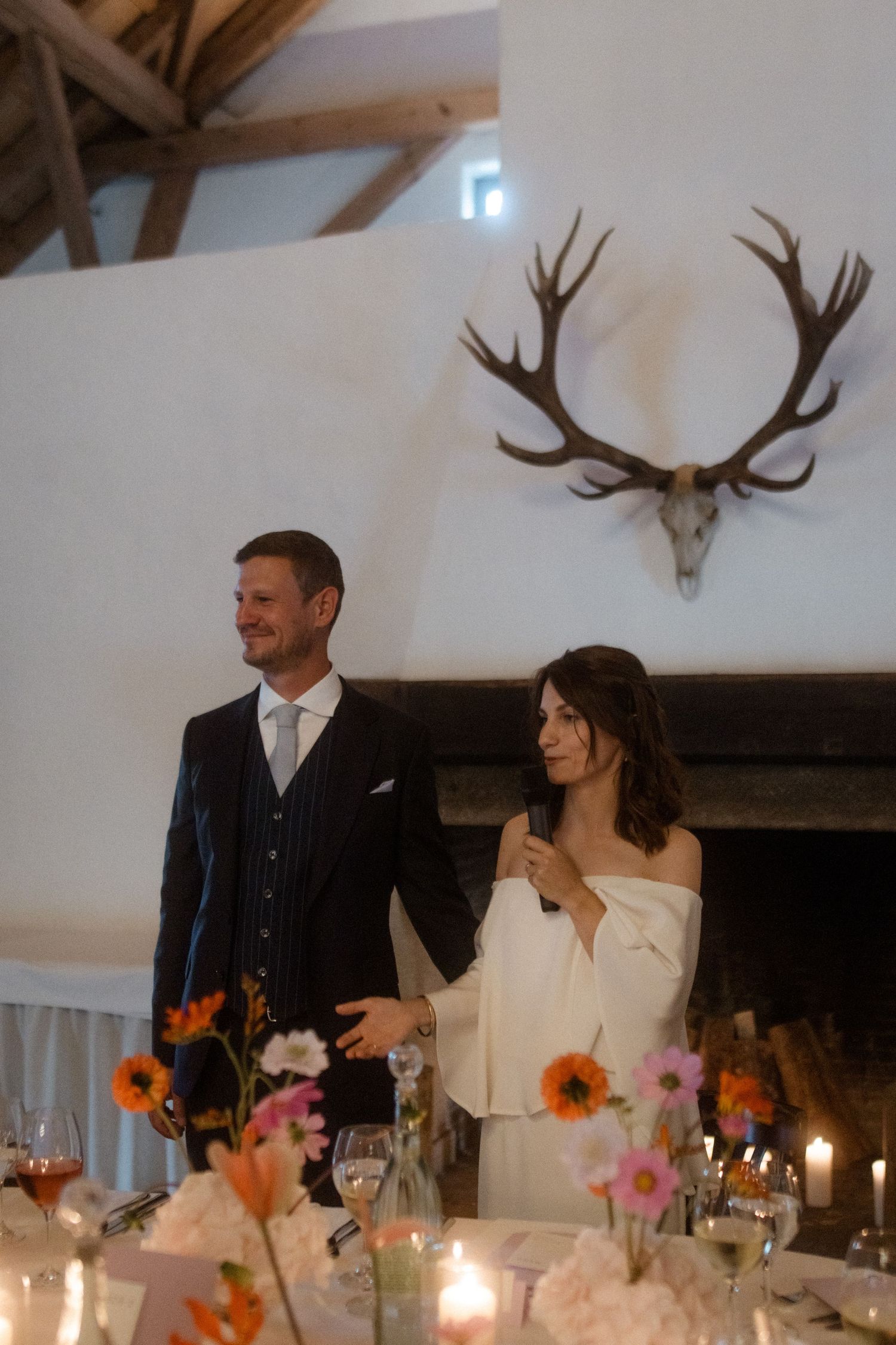 Celebration scene at wedding reception with antler decor and floral table arrangements.