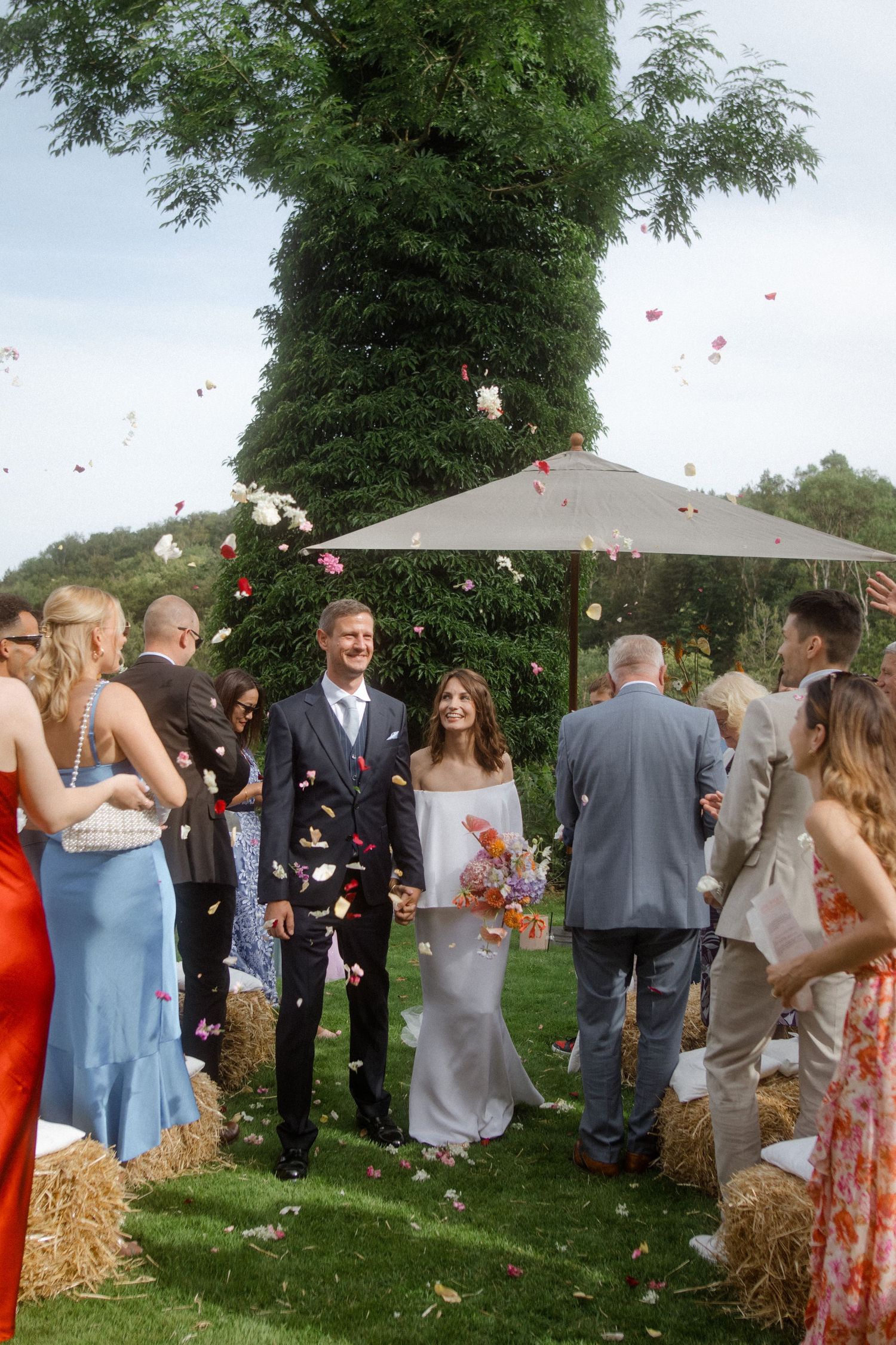 Newlyweds celebrate with guests as confetti falls during their outdoor garden wedding celebration.