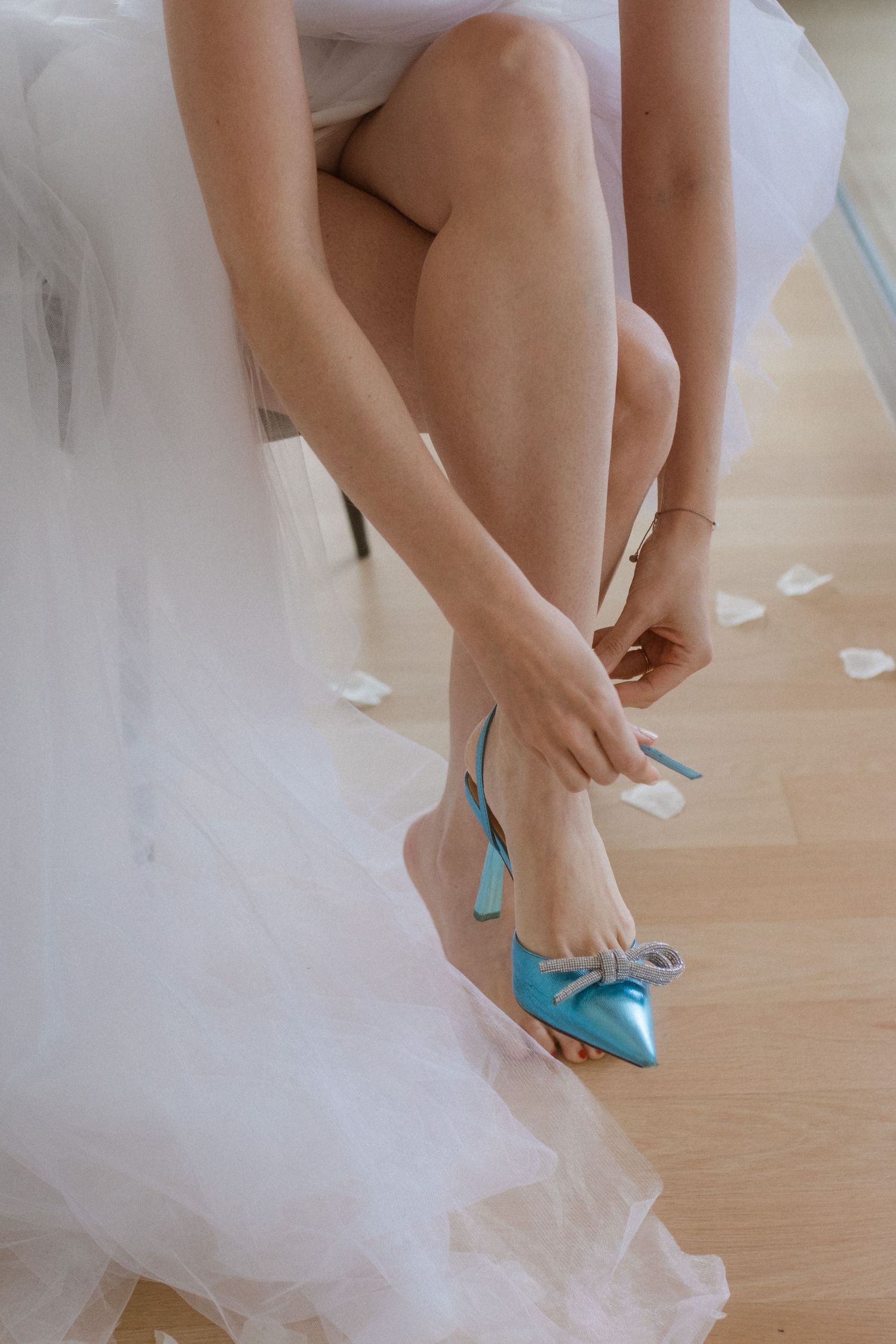 Close up of bride's feet wearing turquoise blue heels with white tulle dress.