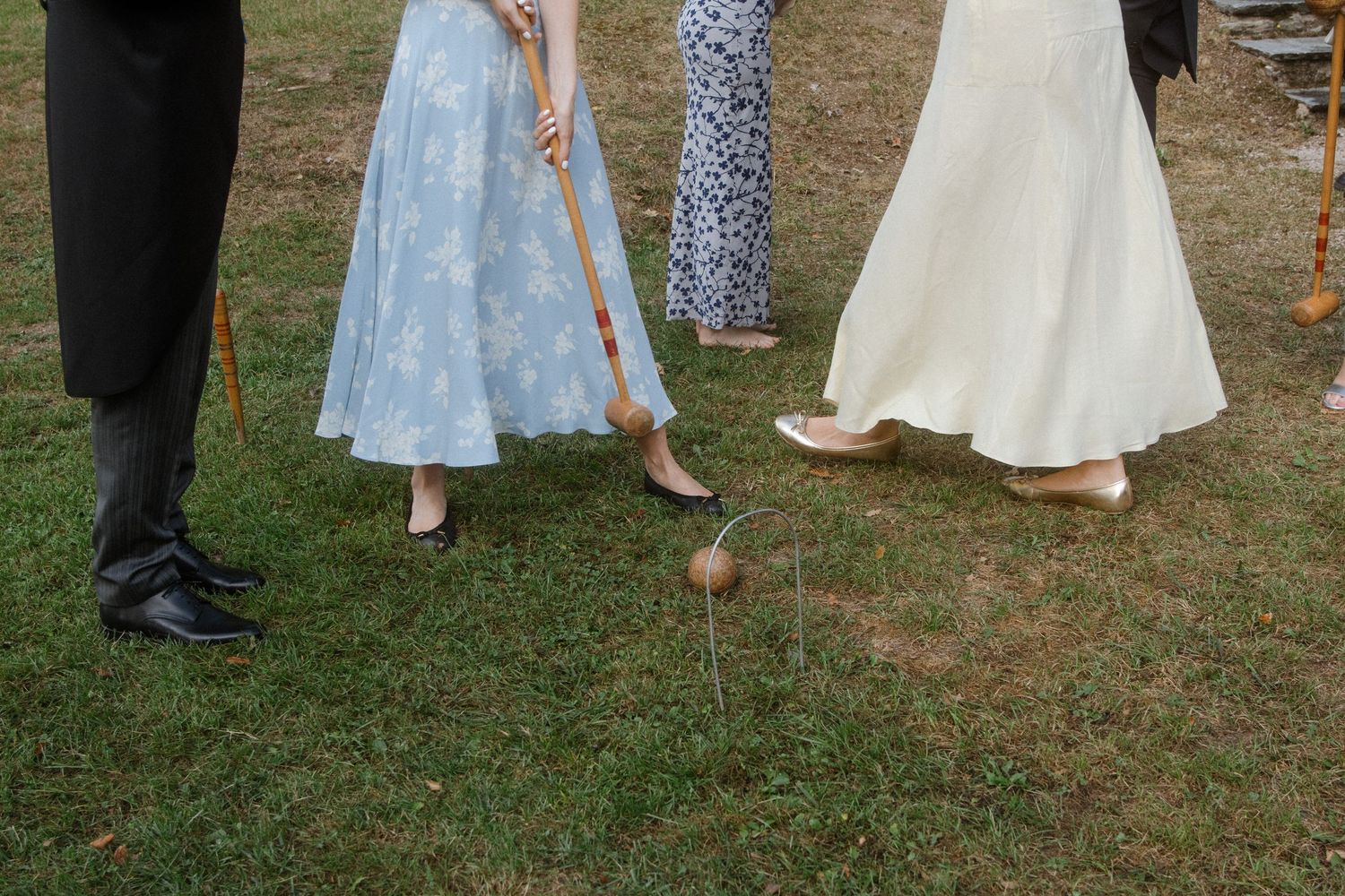 Wedding guests playing croquet on a lawn during an outdoor reception.