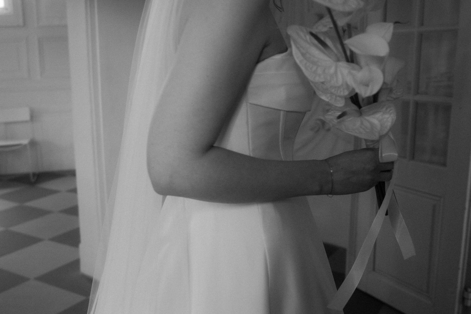 Close-up detail of a white wedding dress against a checkerboard floor.