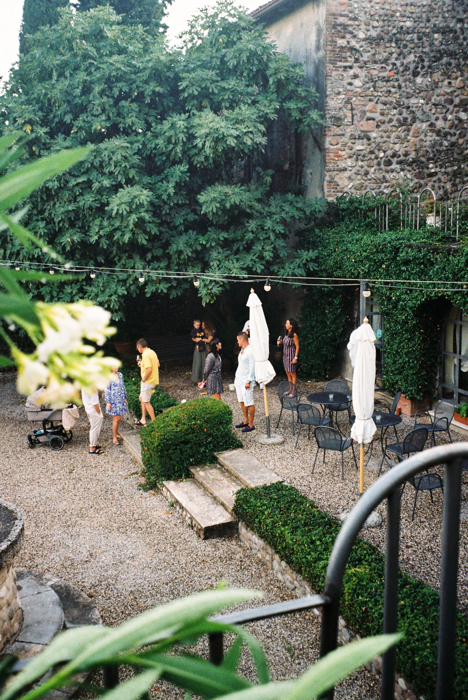 Stone courtyard with string lights and guests mingling during an evening event.