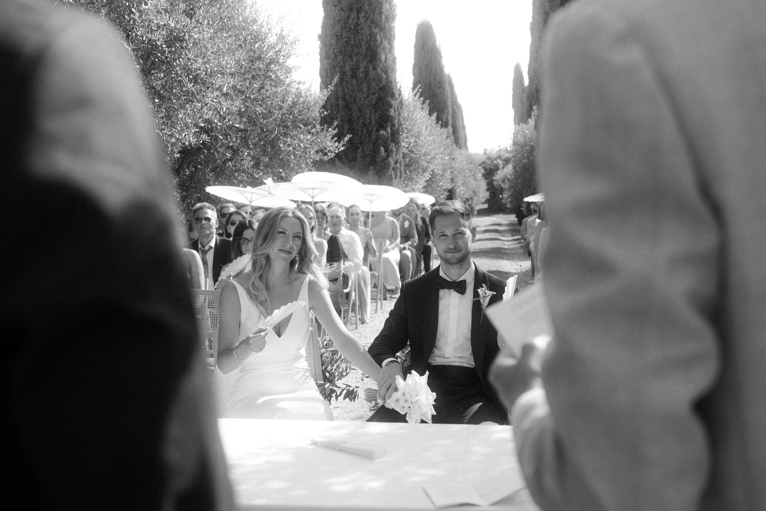 Black and white capture of a wedding ceremony along a cypress-lined path.