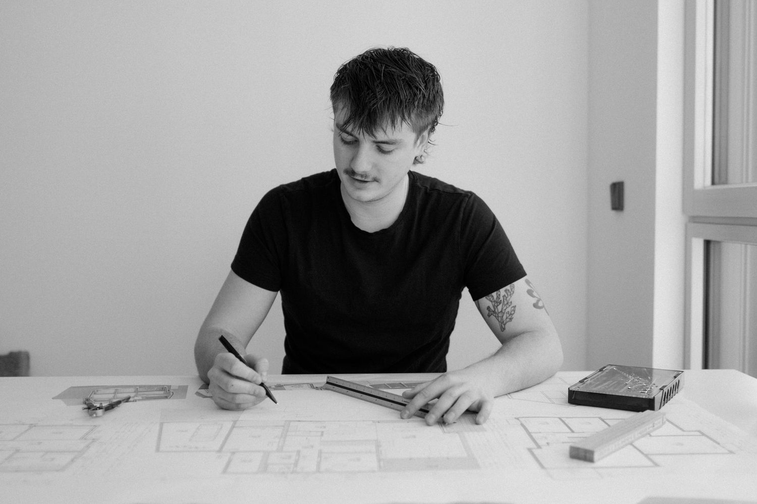 Someone working at a desk in a minimalist setting, shown in black and white photography.