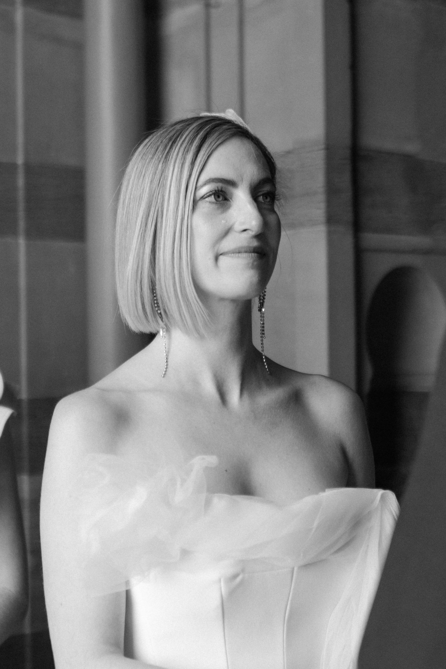 Black and white portrait series of a bride in a strapless wedding gown smiling against a light background.