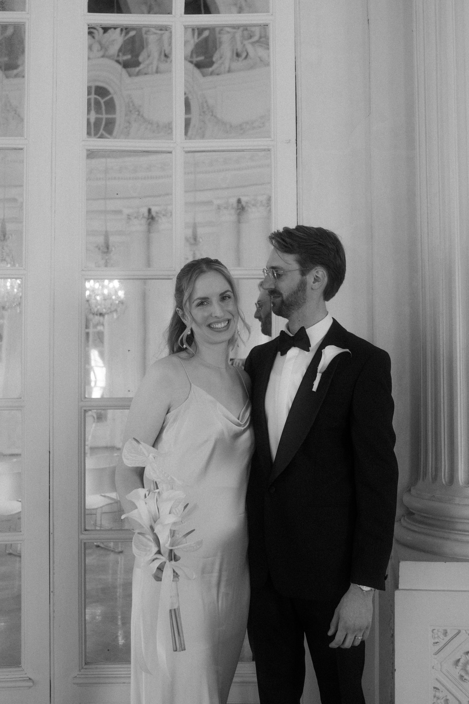 Black and white portrait of a couple sharing a tender moment in an elegant interior setting.