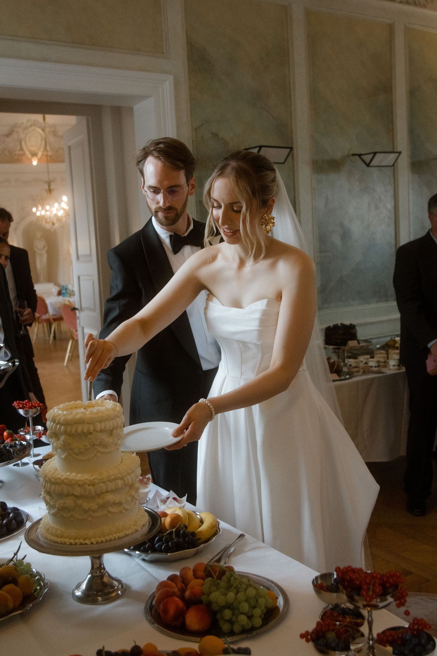 Newlyweds working together to cut their wedding cake at the reception.