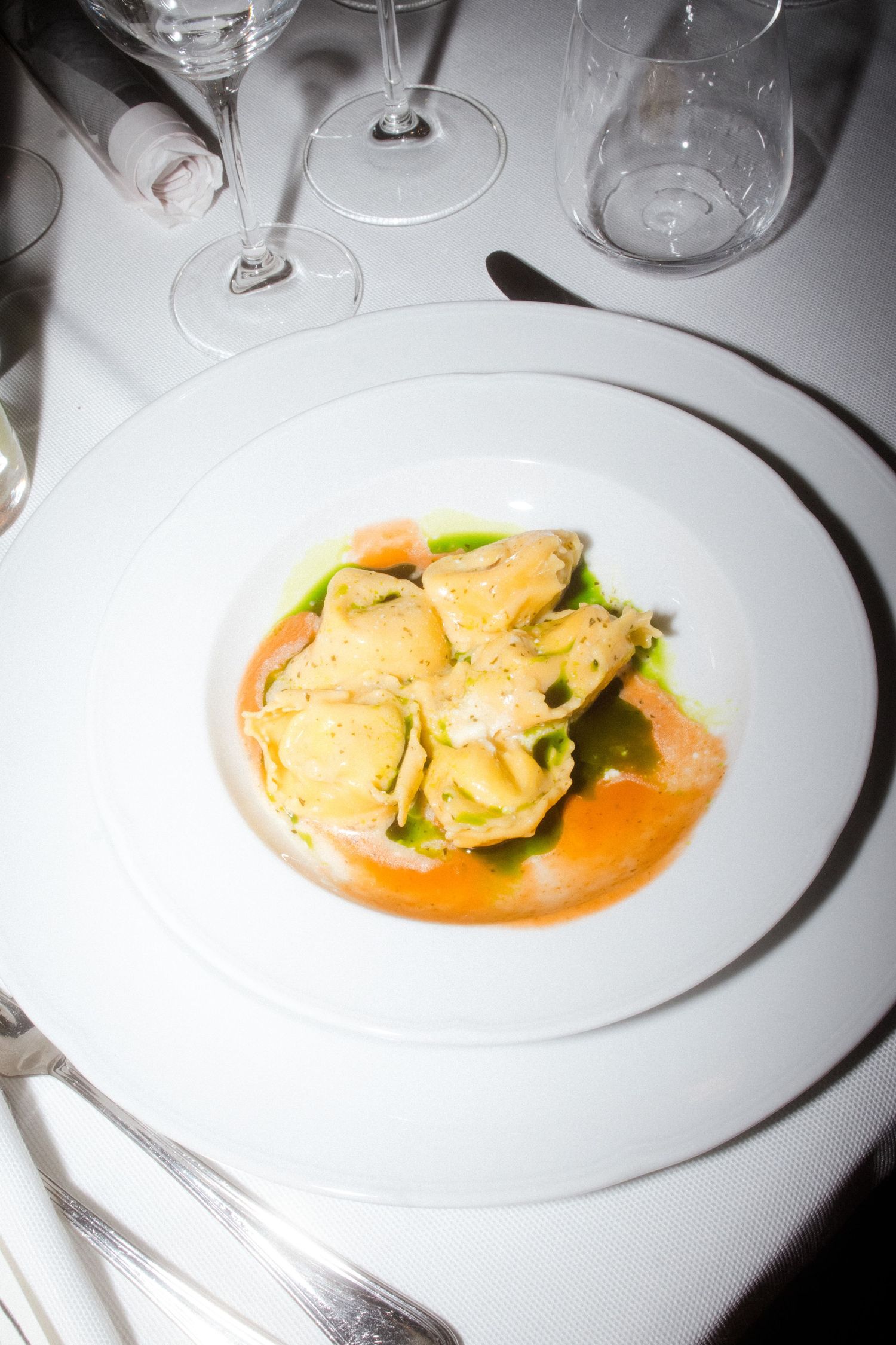 Elegant pasta dish with ravioli in orange sauce served on white plate.