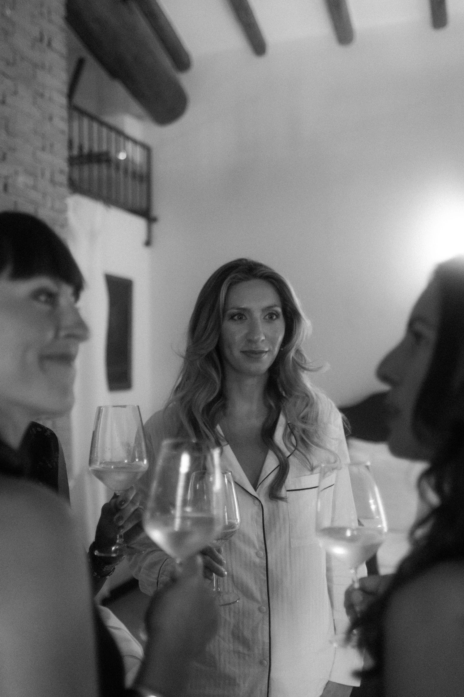 Black and white photo of people holding wine glasses during a social gathering.