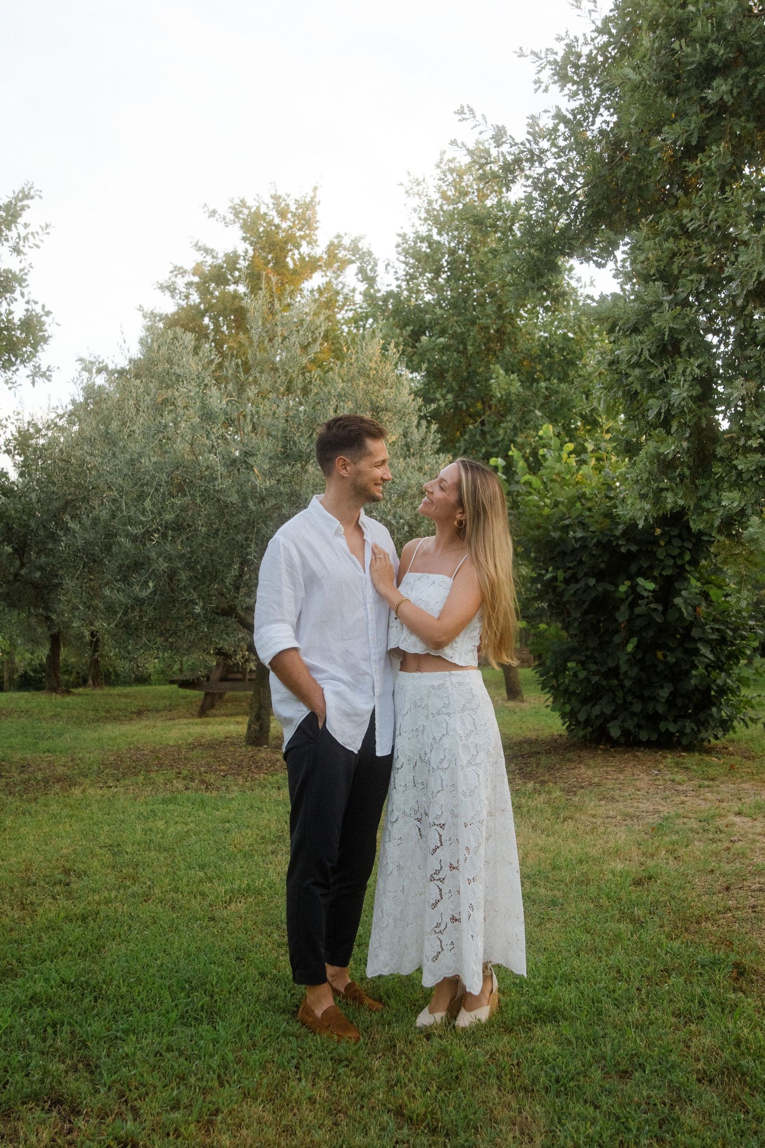 Romantic couple embracing in garden setting during sunset.