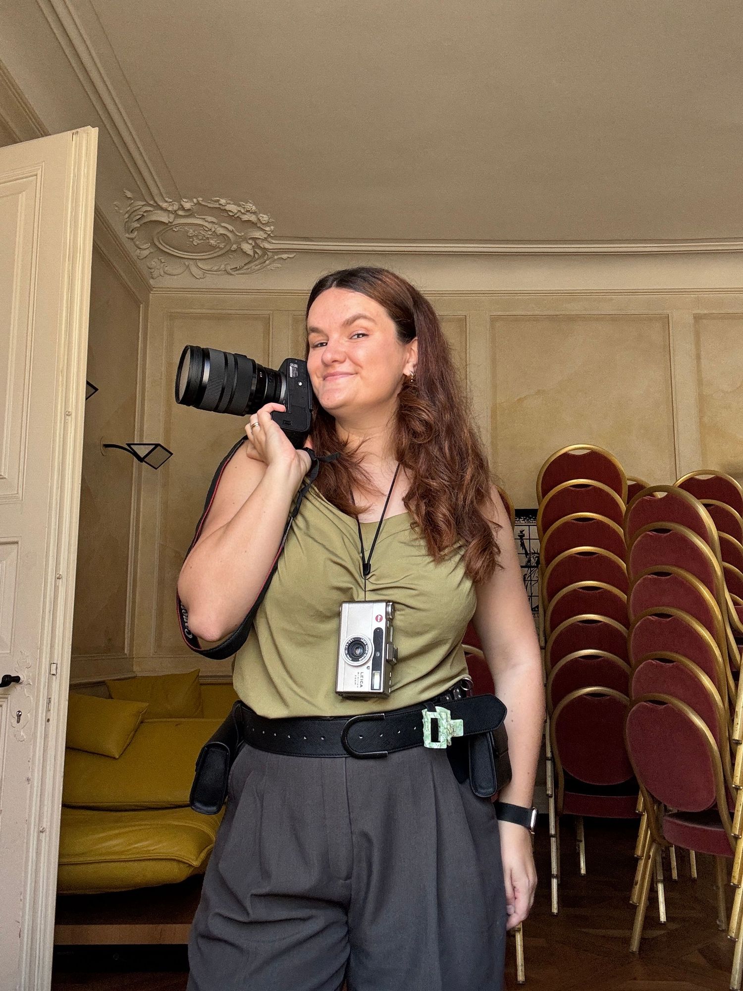 Photographer in olive shirt and dark pants demonstrates camera positions in an indoor venue.