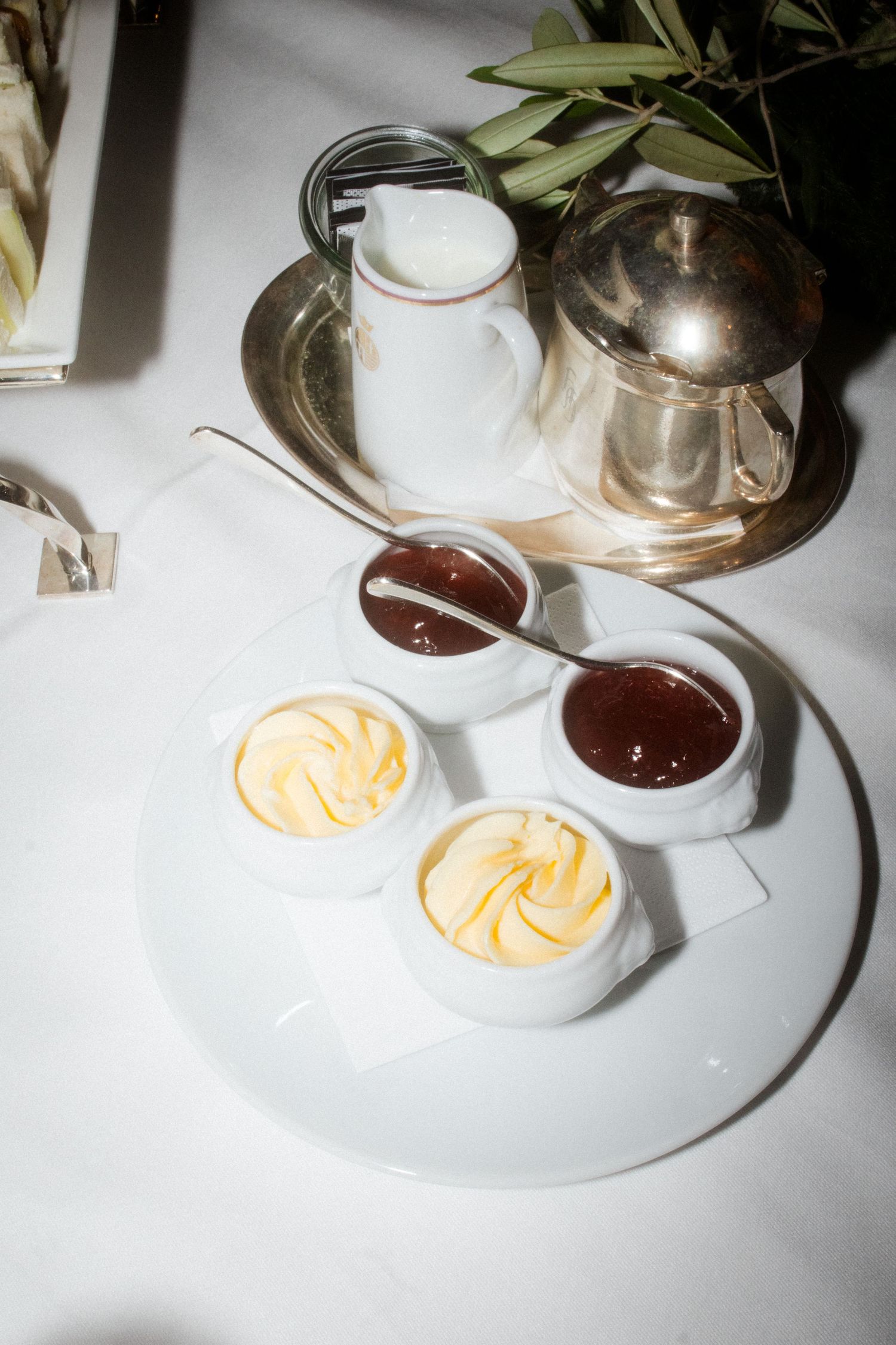 Elegant table setting with butter curls and chocolate sauce in white ramekins on a silver tray.