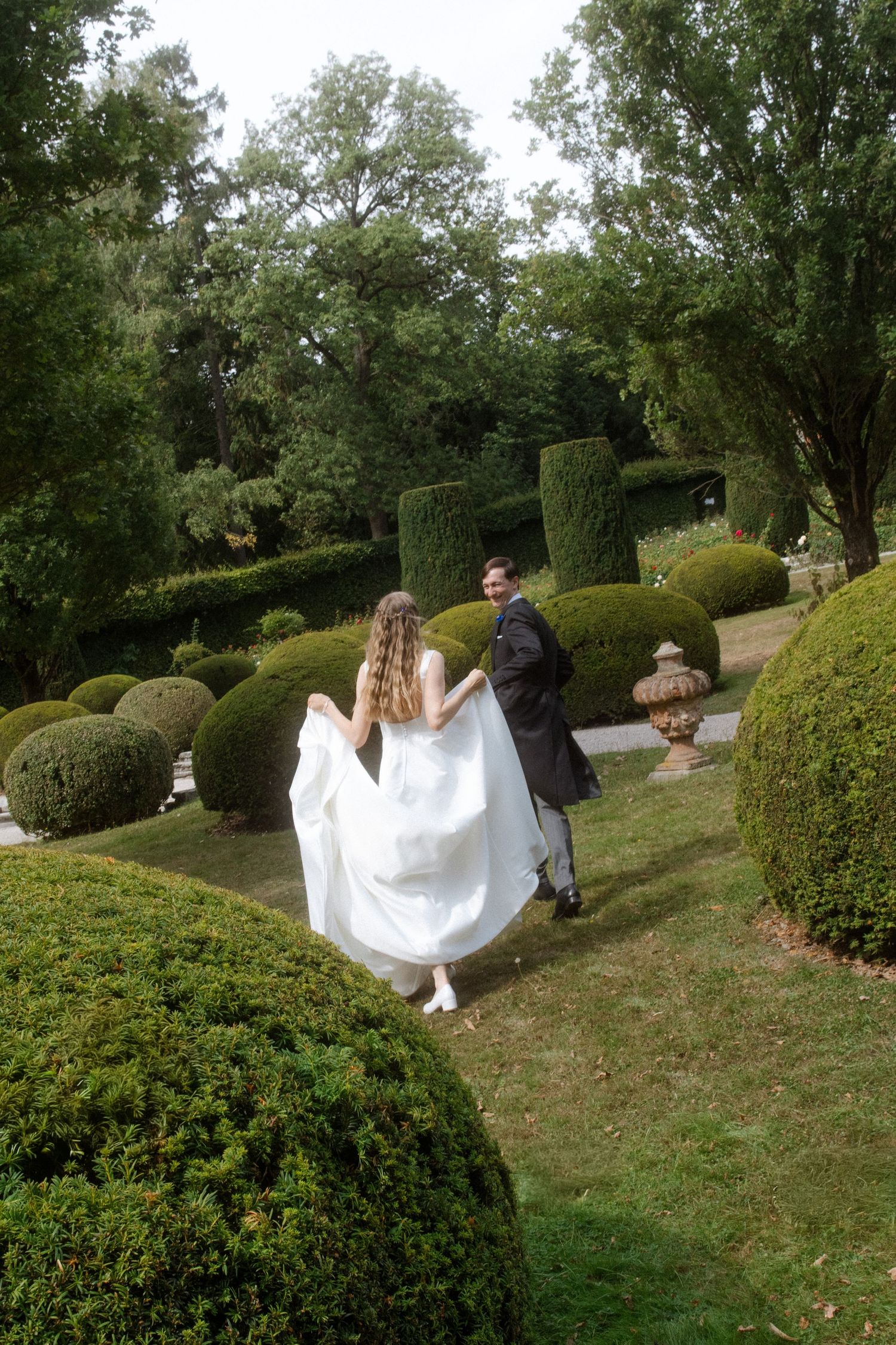 Wedding photography session taking place in a formal garden with sculpted bushes.
