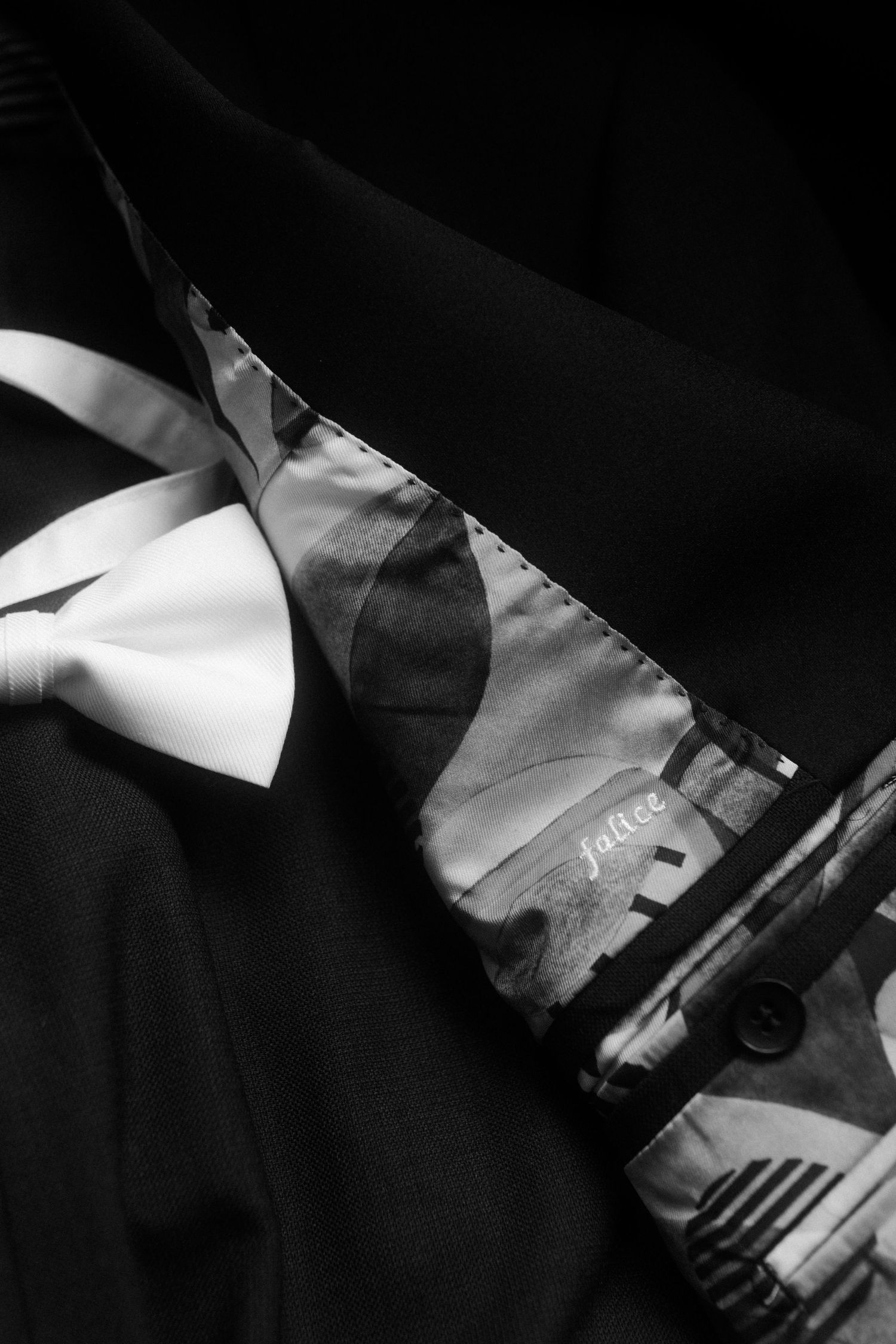 A close-up black and white detail of a formal bowtie and suit fabric.