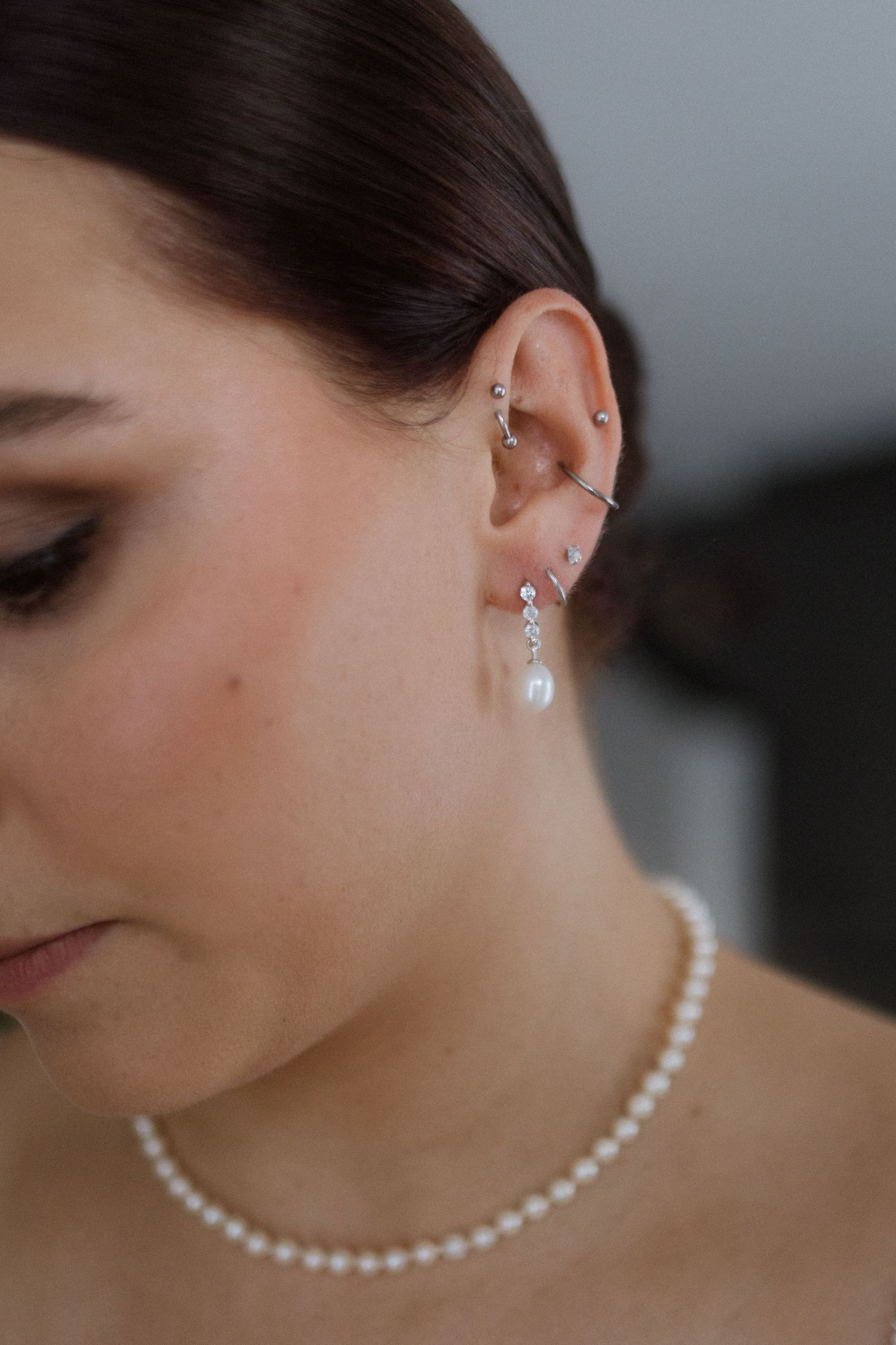 Elegant bridal jewelry featuring a delicate pearl necklace and crystal drop earrings in a close-up profile shot.