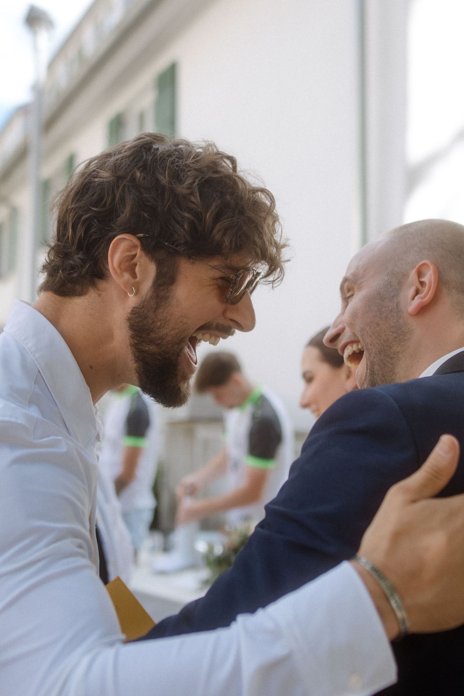 Guests share laughter and hugs during an outdoor wedding reception.