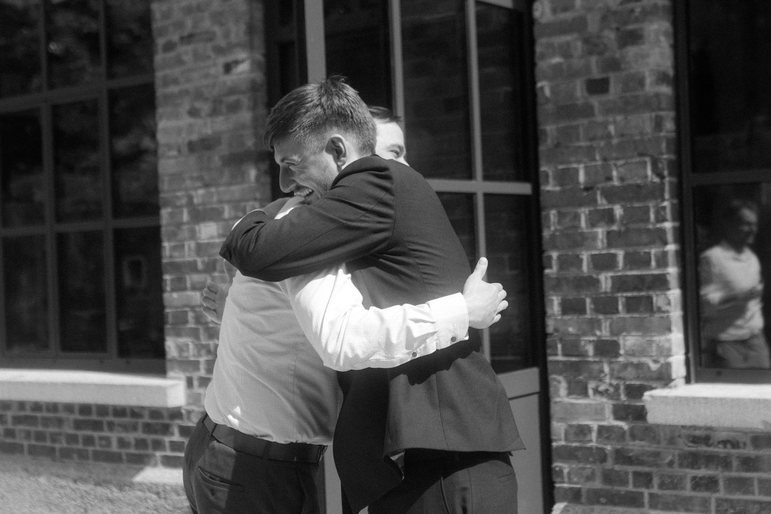 A tender black and white embrace captured against a brick building exterior.