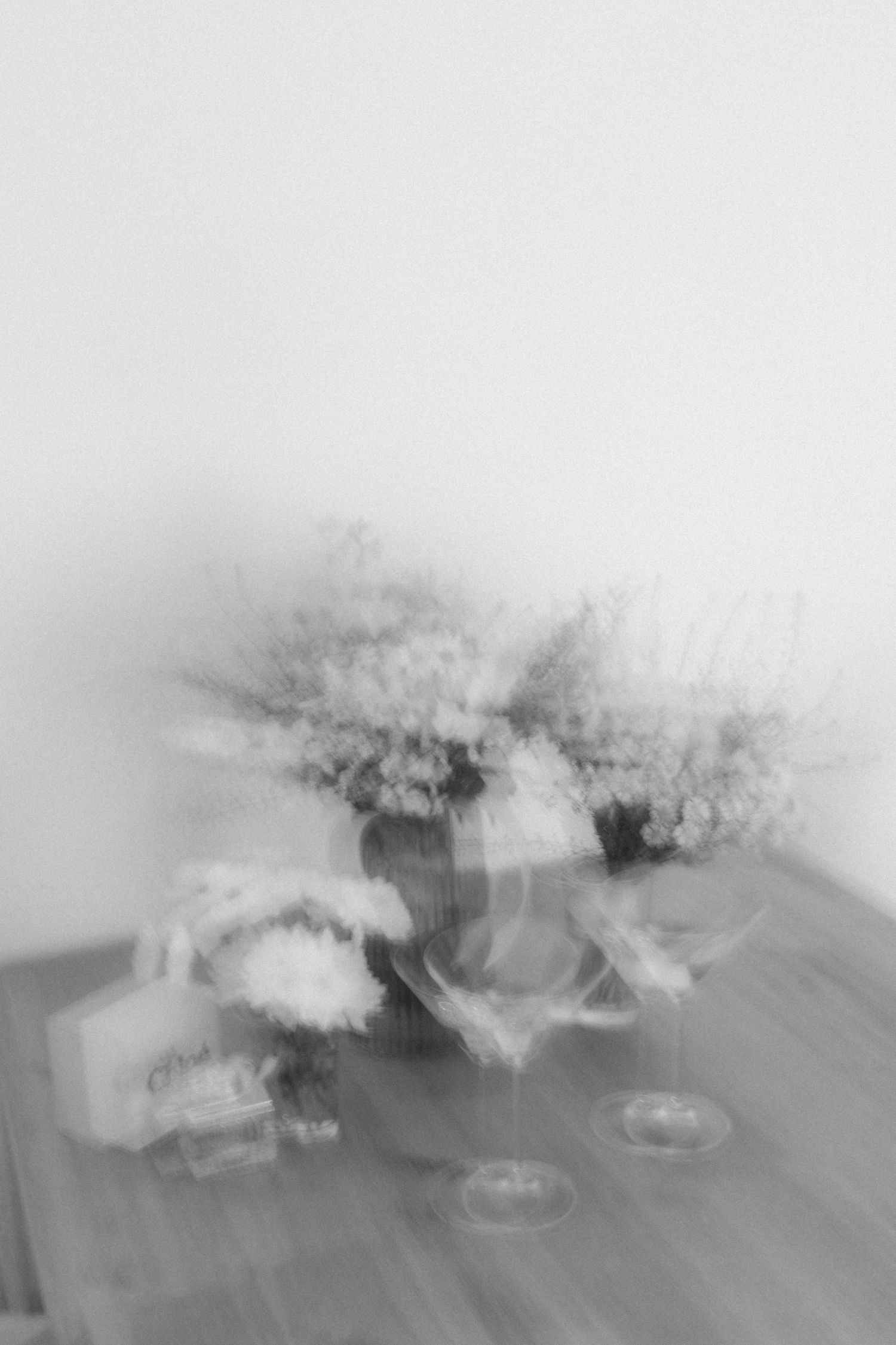 Abstract blurred image of wedding decor with flowers and glasses on a wooden surface.
