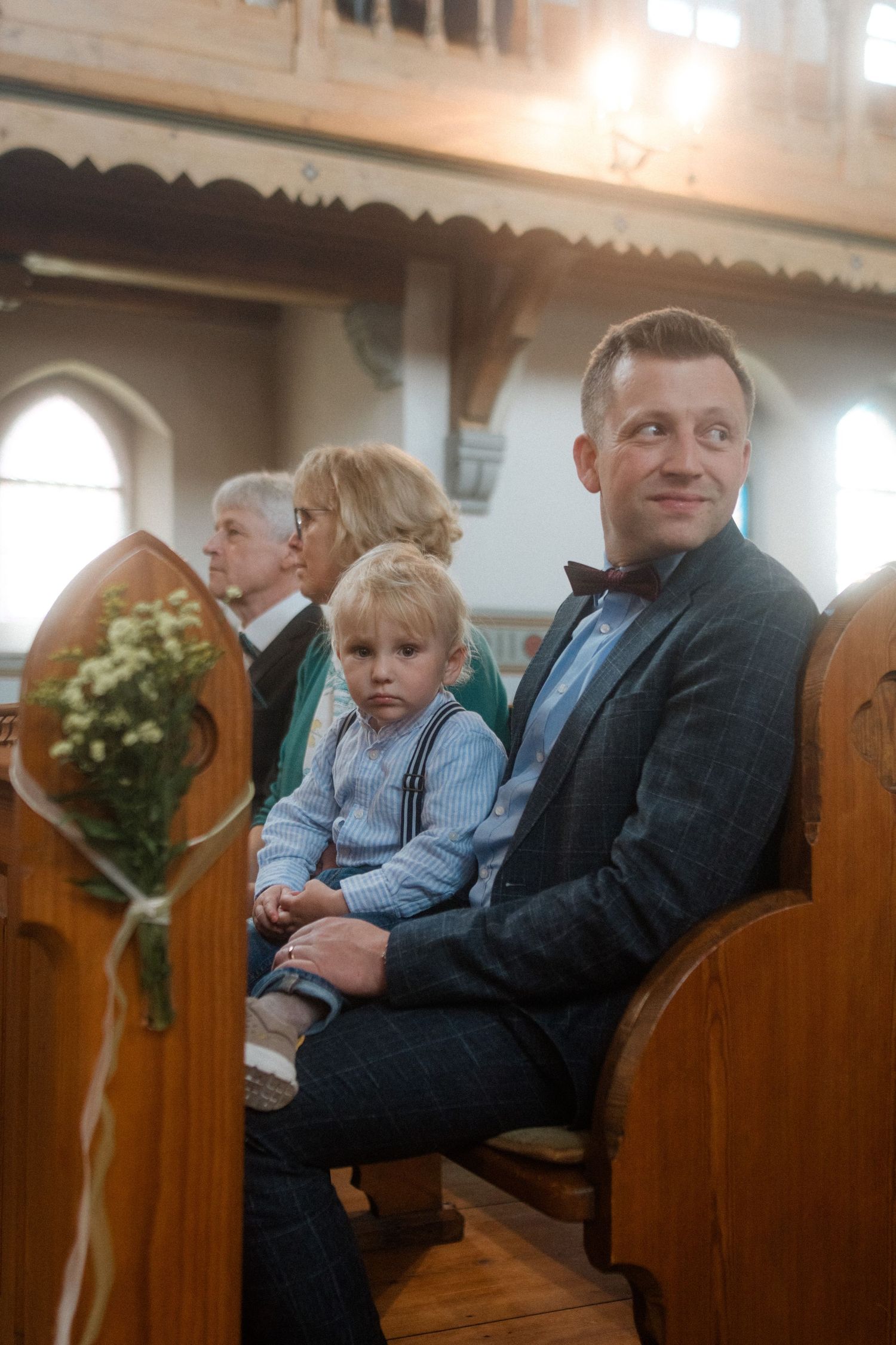 A church congregation gathers together sitting in wooden pews during a service.