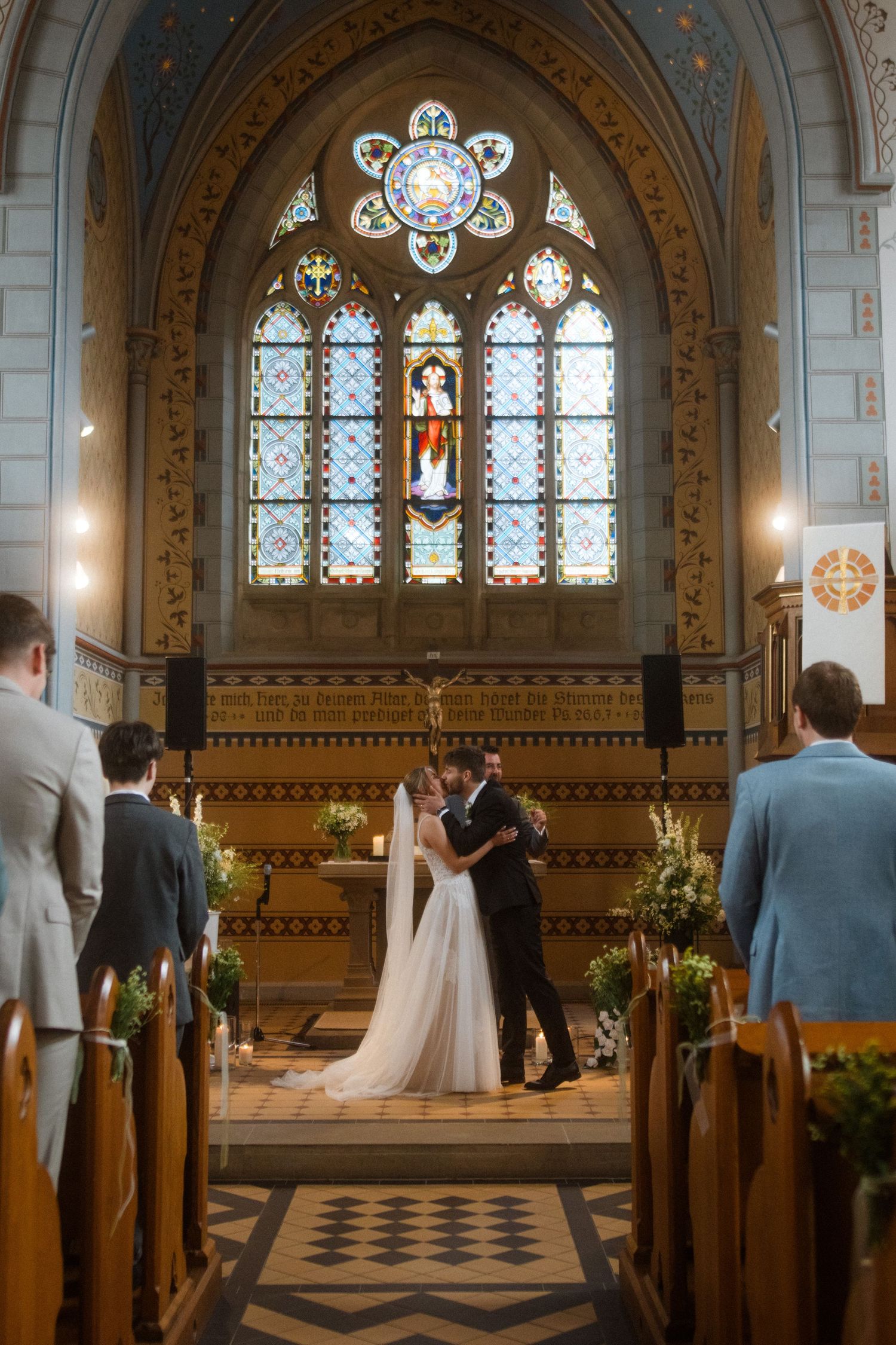 Wedding ceremony in a beautiful gothic church with stained glass windows and ornate architecture.