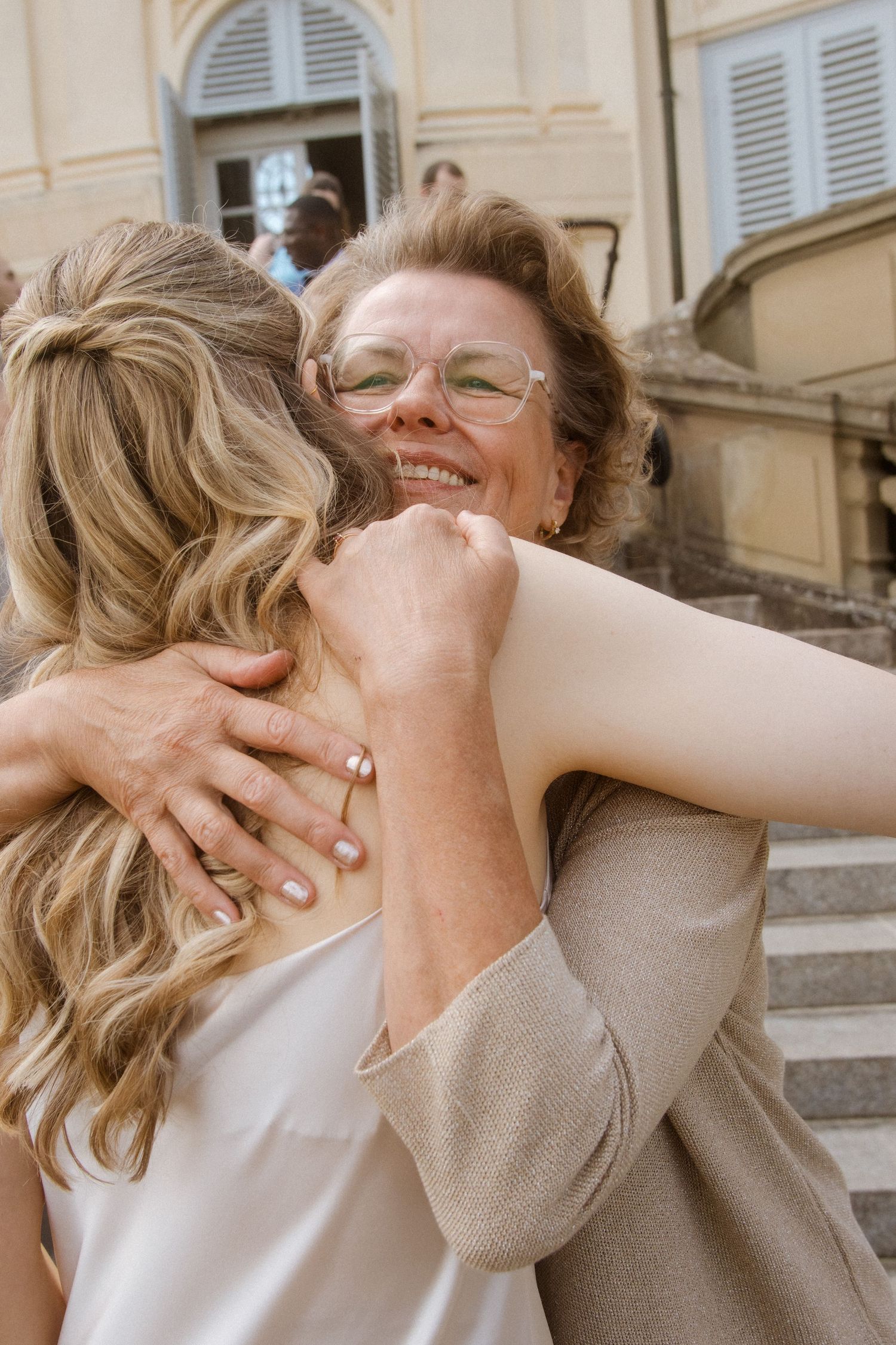 Two women sharing a joyful embrace and laughter in warm natural lighting.