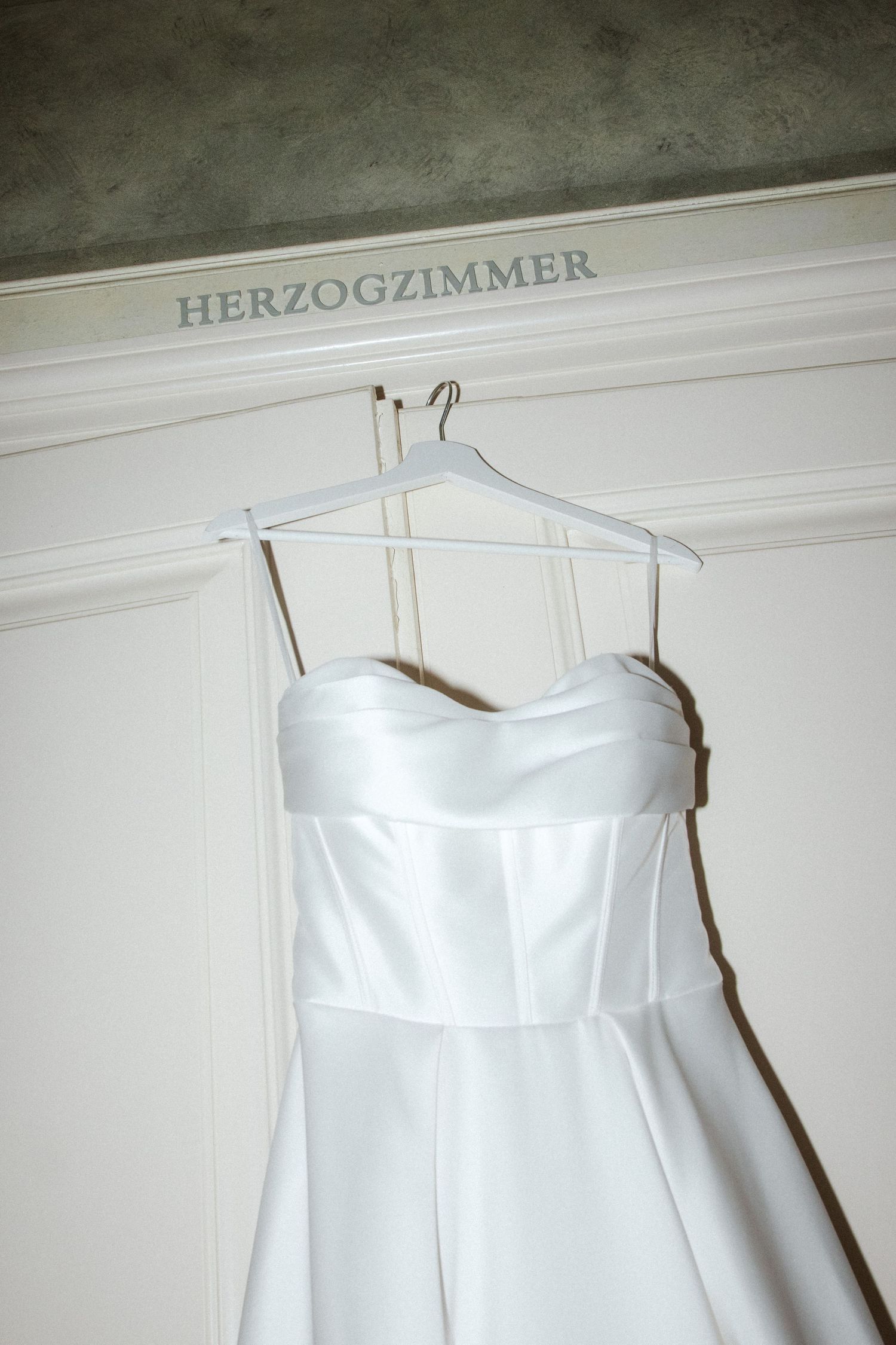 Close-up view of a white strapless wedding gown hanging in the Herzogzimmer.