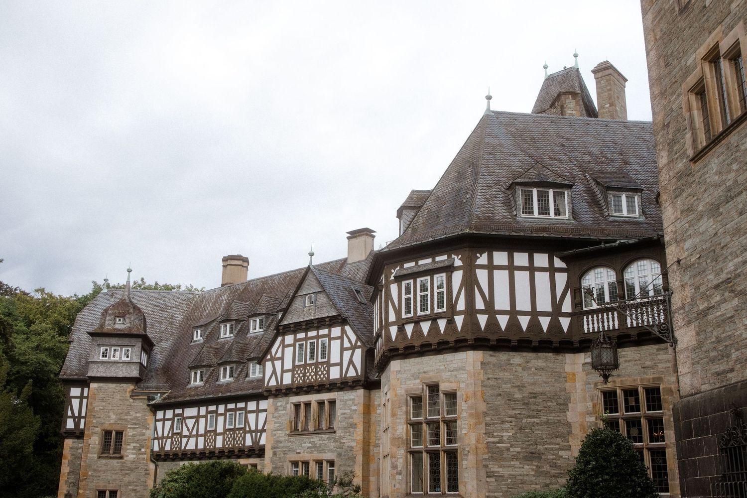 Historic Tudor-style architecture with stone walls and timber framing against cloudy sky.