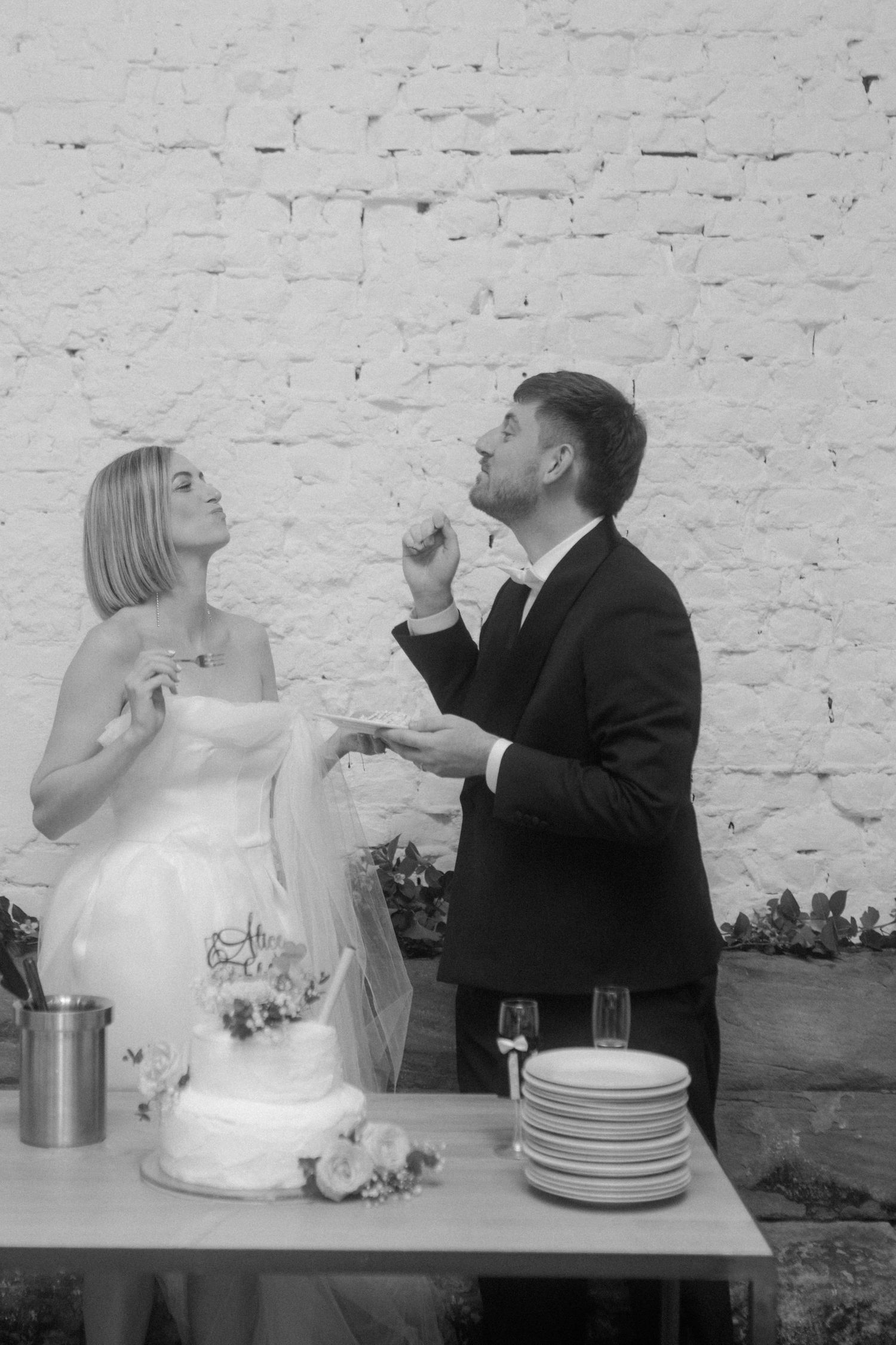 A couple shares a playful moment while tasting their wedding cake at the reception.