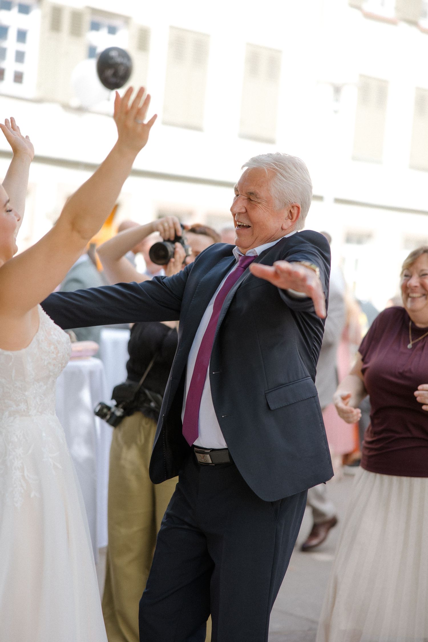 Wedding guests playing with a balloon during a lively outdoor celebration.