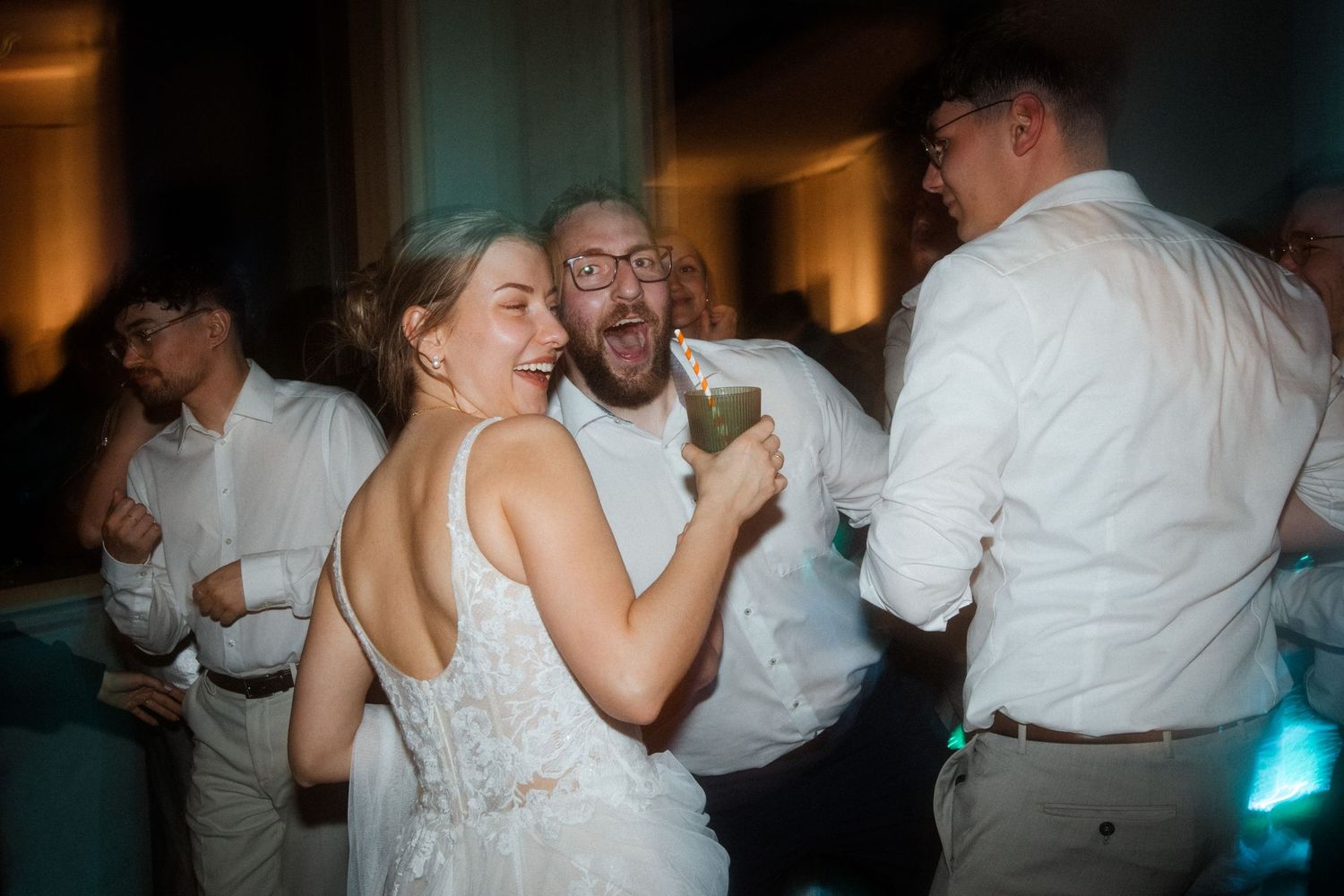 Joyful couple dancing and singing together at their wedding reception in dim lighting.