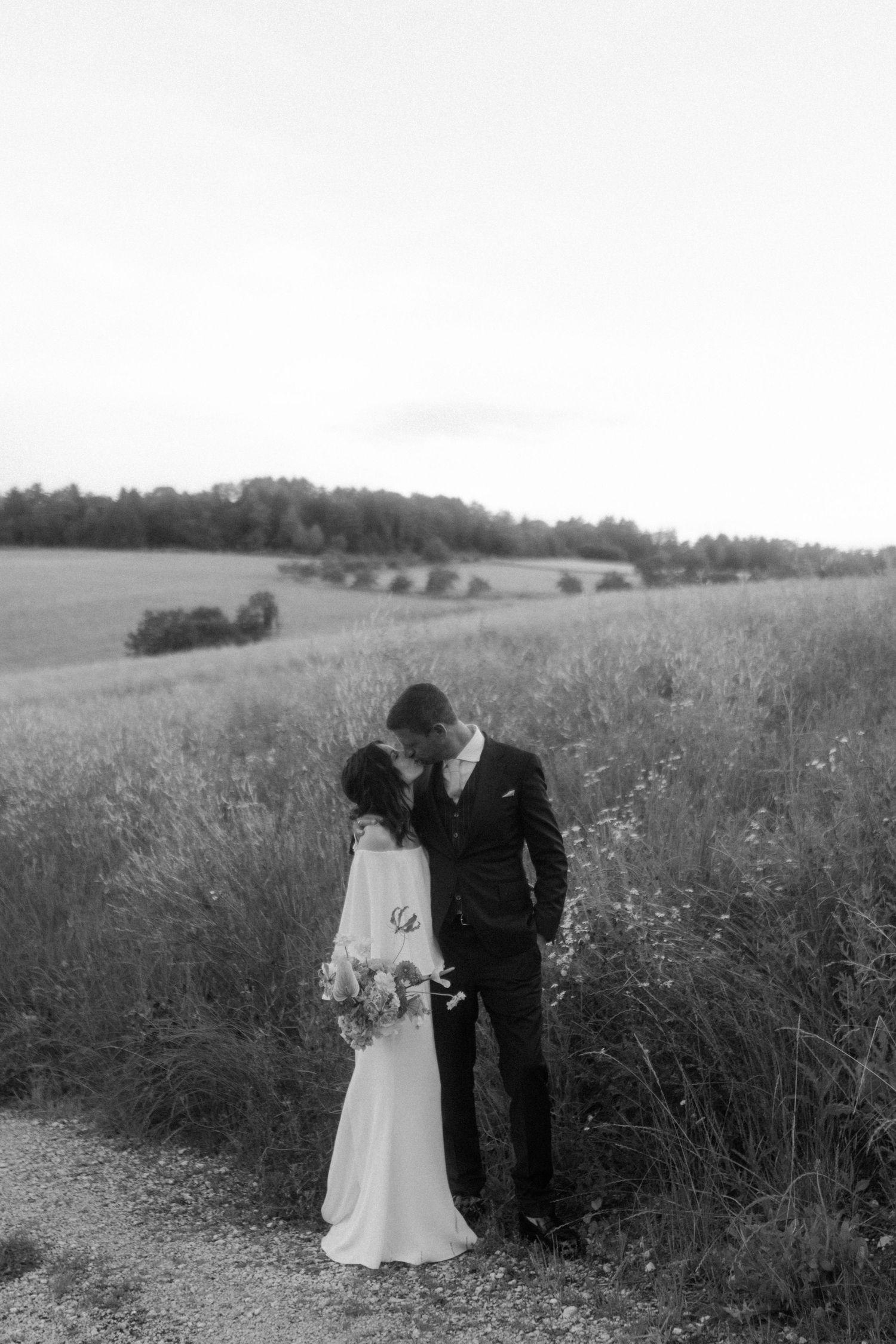 A romantic black and white portrait of newlyweds in a meadow.