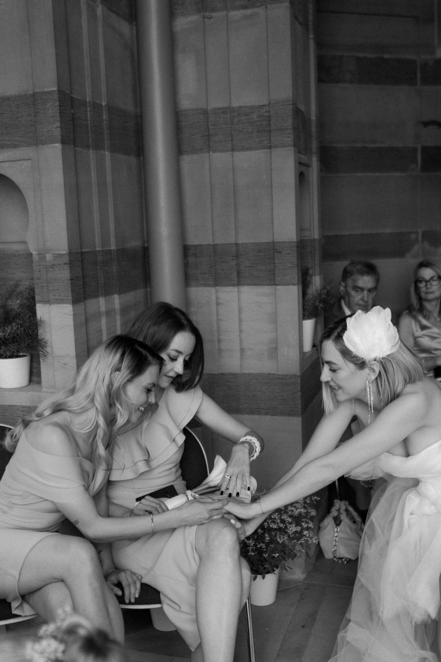 Black and white photo of wedding party members interacting in an architectural setting.