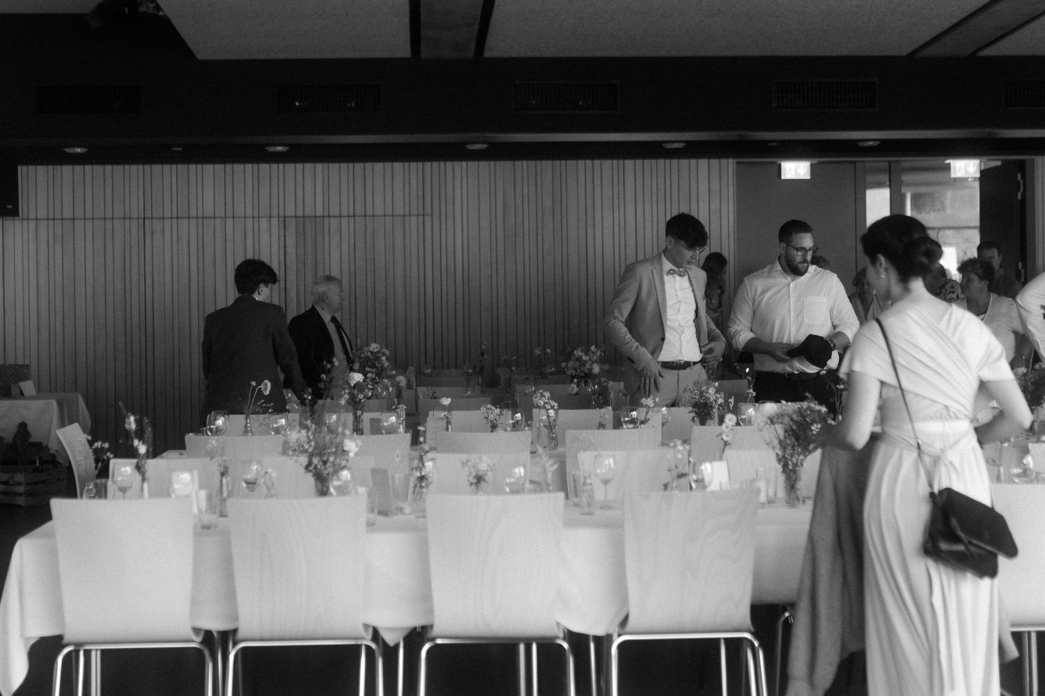 Black and white photo of a dining room setup with white chairs and table settings.